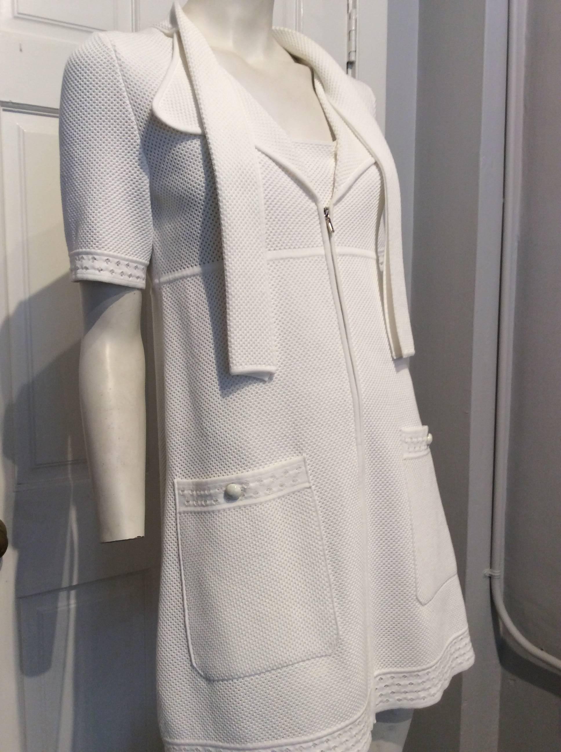 Chanel white cotton pique dress.  This sporty but feminine mini dress has a banded collar that transitions to folded ribbons, that trail to the waist, wide lapels, zip enclosure in front, and a triangular inset at the neckline.  The two square hip