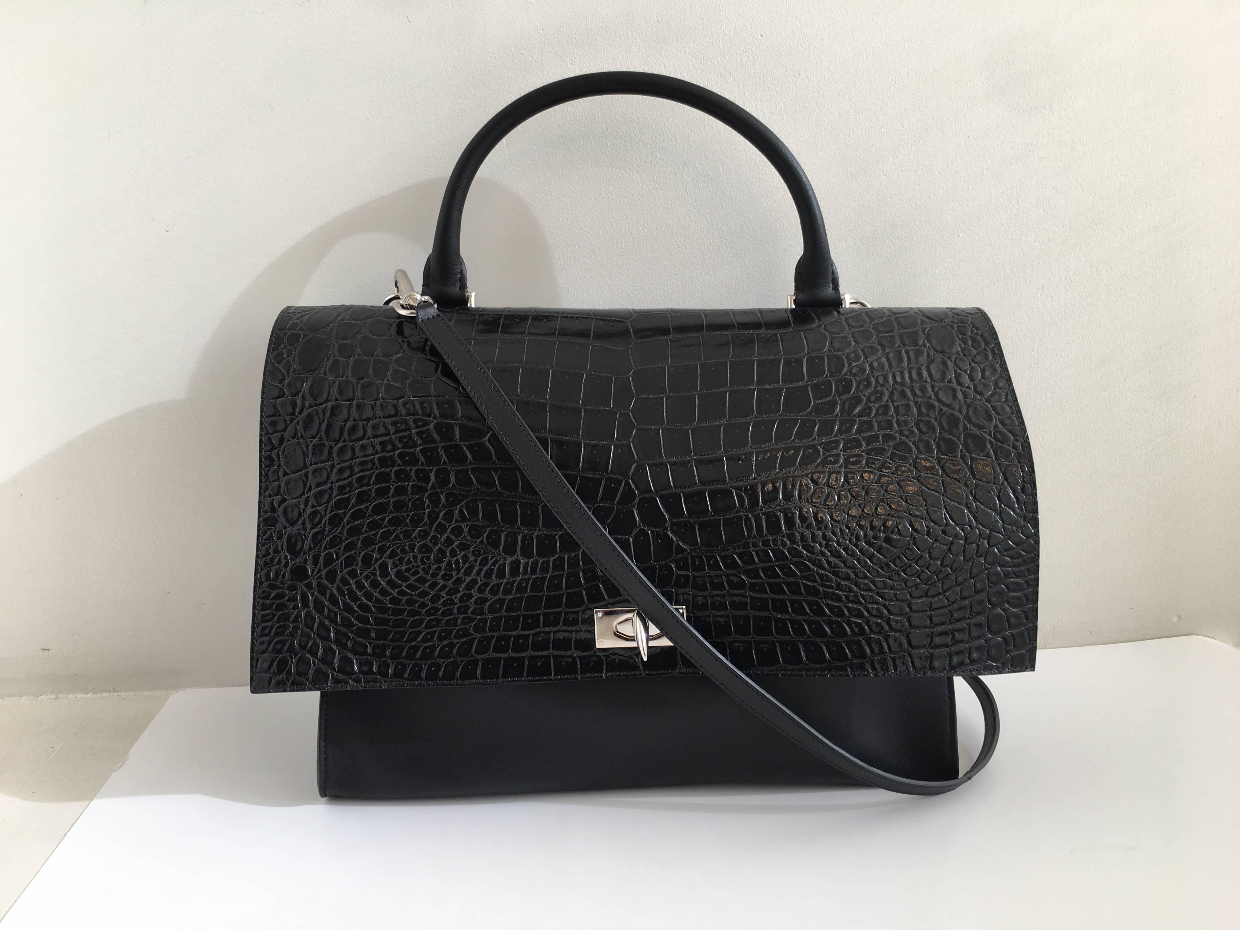 Black Givenchy 'Shark' bag crafted in Italy in black calf leather and a mock croc wider flap. It has a top handle and a detachable shoulder strap. The twist lock is the iconic shark tooth in silver colored metal. It features a large interior pocket