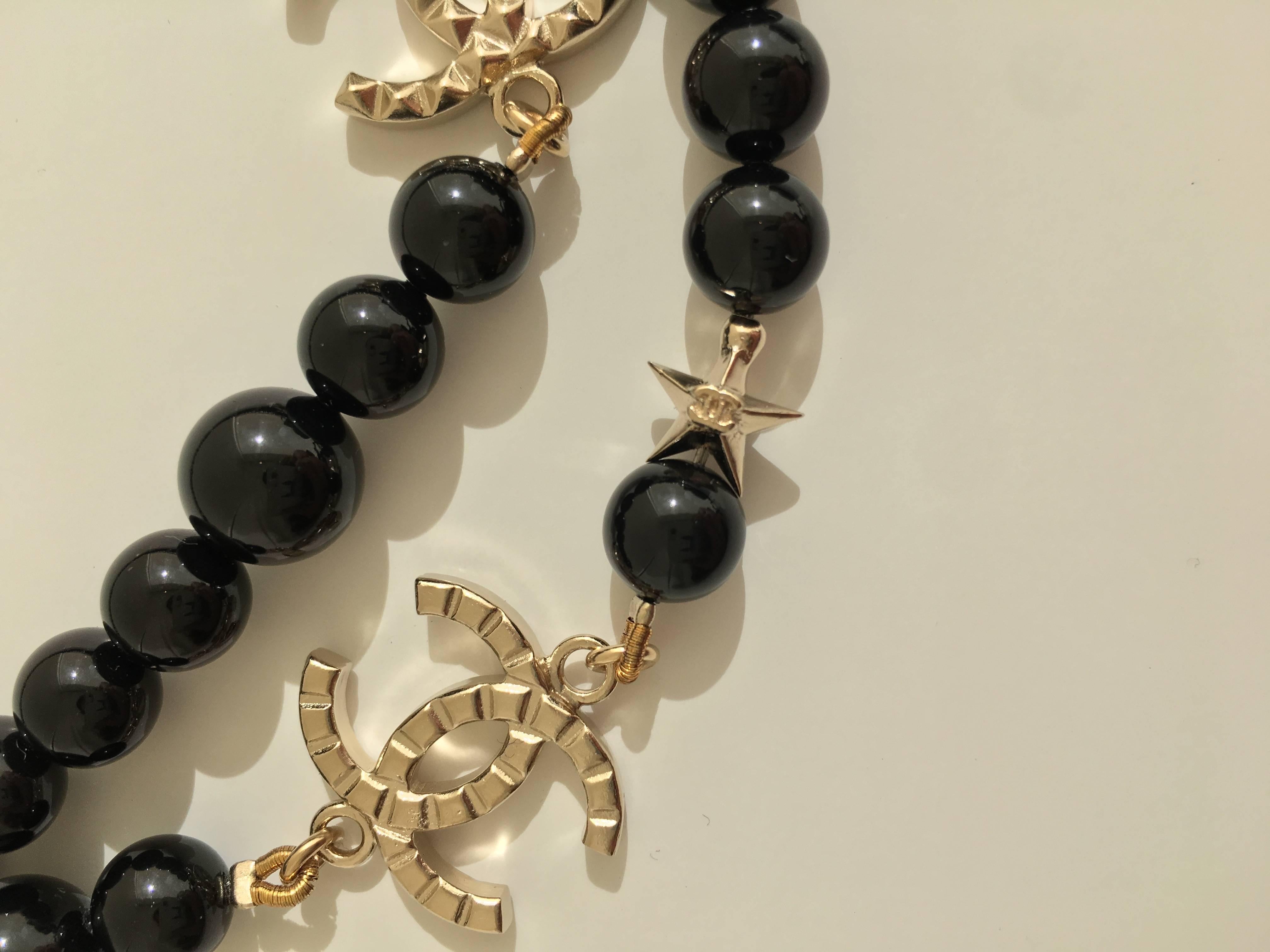 This charming Chanel black and muted gold beaded necklace has the iconic metallic CC Logo repeated through out it's length.  A tiny silver CC logo embellishes the clasp chain. 