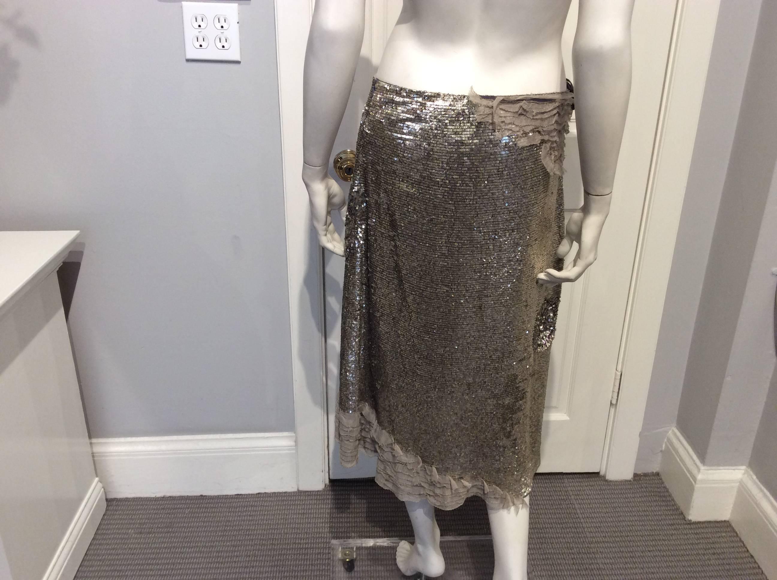 Silver sequin Maurizo Pecoraro skirt with a row of taupe chiffon soft ruffles on the right side of the waist as well as partially in the front and back of the hem. The back is slightly longer than the front by 2.5 in. The skirt sits under the waist.
