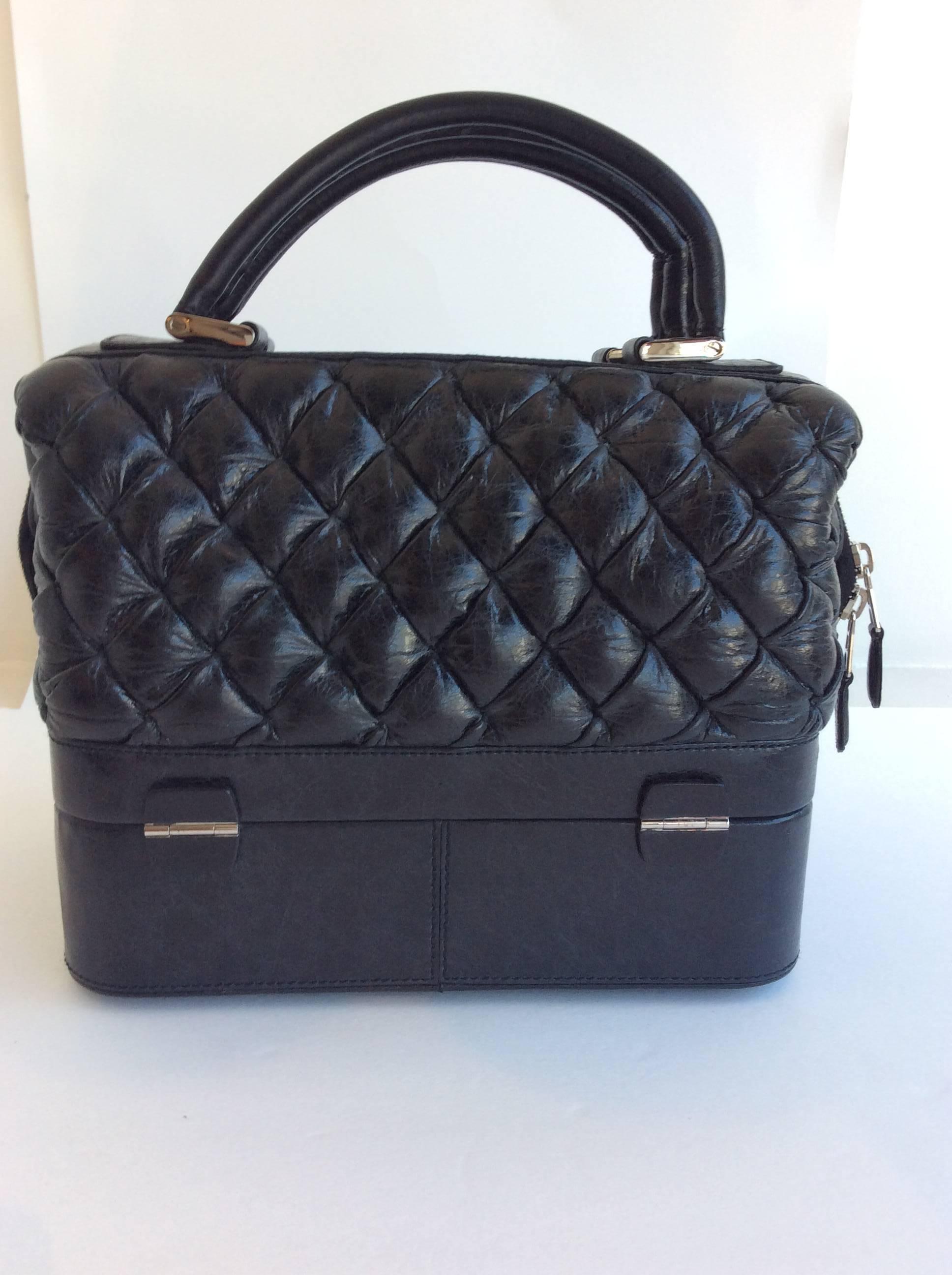 Balenciaga black leather quilted bag with silver hardware. Easy to carry with two leather handle straps. Has deep compartment up top which zips, as well as opens on the bottom with two silver snap buckles. Attached is a small mirror tucked inside a