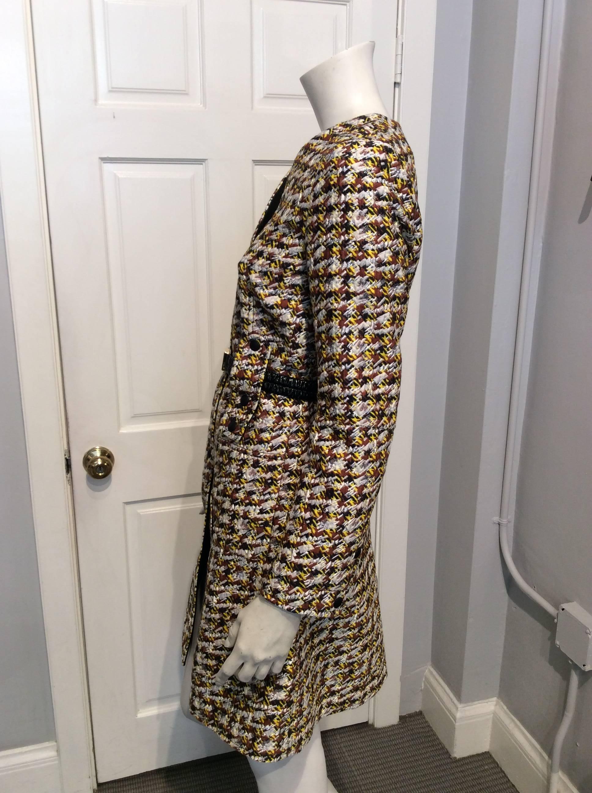 Long coat with tweed like appearance (colors are yellow, brown, and white).  Leather covered snap button enclosures.  Shiny black belt with gold buckle.  Leather trim inside coat.