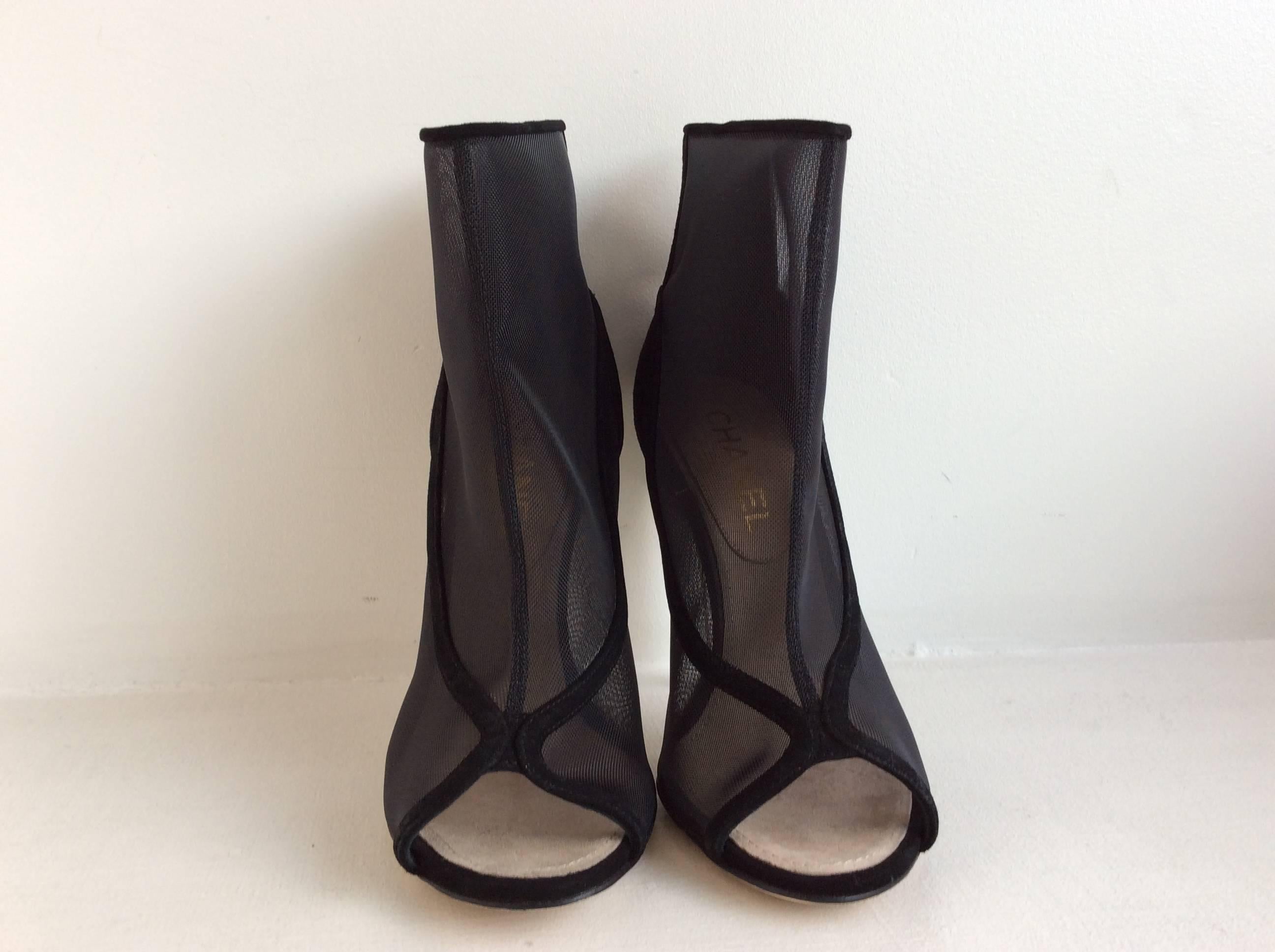 Chanel black nylon mesh and suede open toe booties in size 39 (8.5 USA).
The clear acrylic heel is 4.5 inches. The booties back is in black suede with two small gold toned CC on each of the outer upper part. For easy wear they have a 4 inches zipper