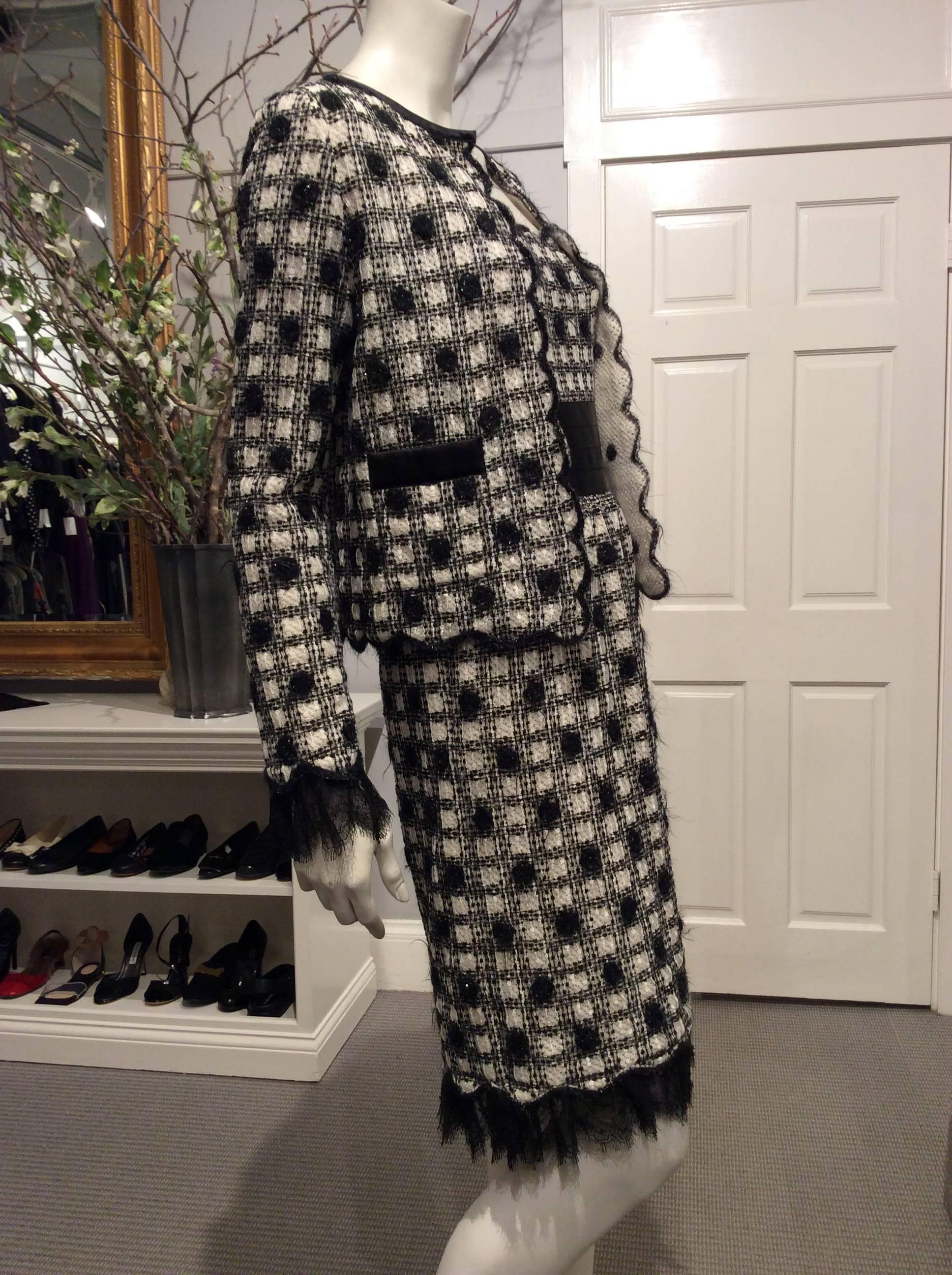 An off white cashmere knitted layer is covered by black and white checkered lace with black mohair polka dots. This dress has a satin mock cummerbund with two small pewter jeweled CC on the side. The skirt is slightly gathered at the waist. The