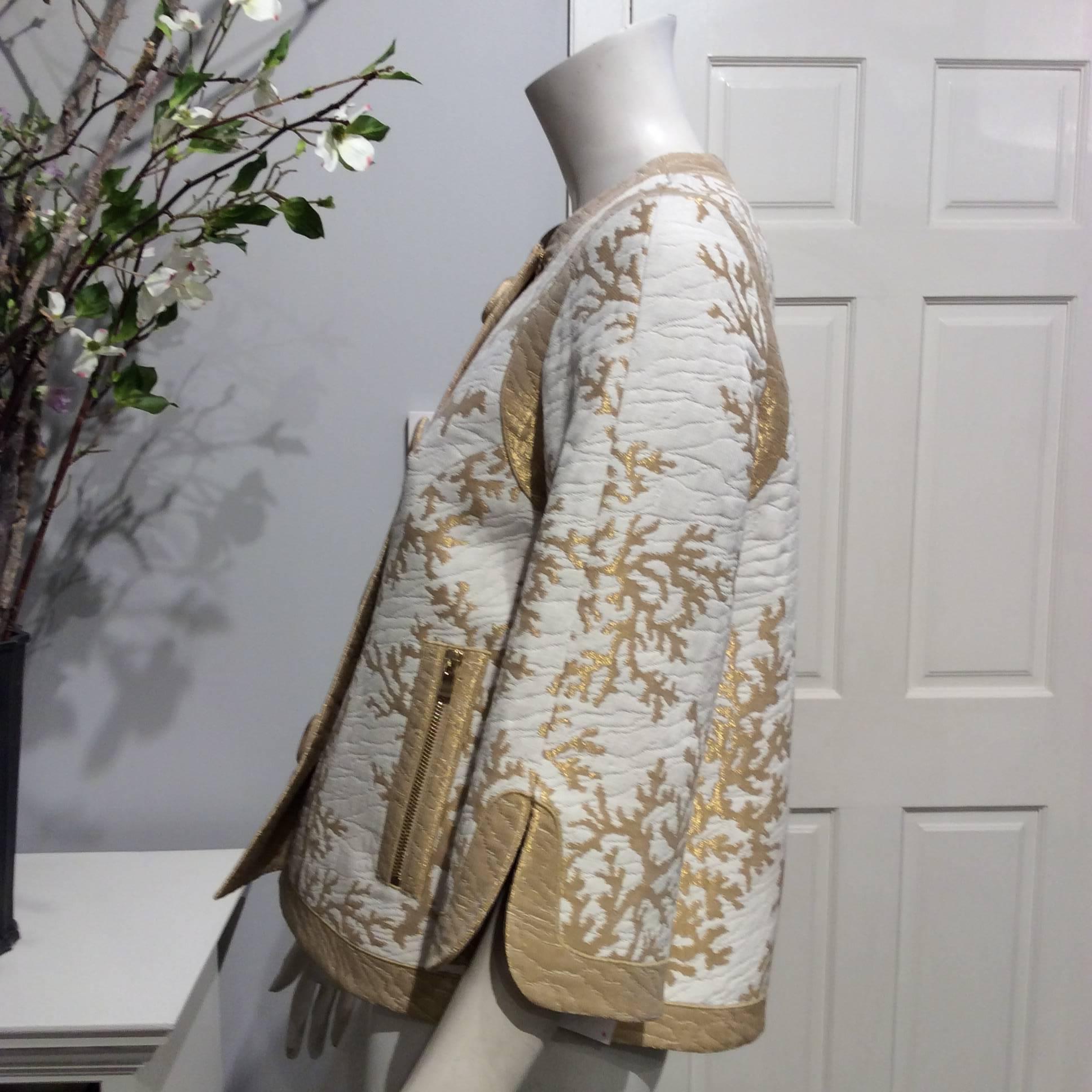 This wonderful Asian inspired jacket is in ivory brocade with a weave of gold coral branches. It closes with 4 big buttons covered in gold fabric. The two front gold pockets close with gold zippers. The slightly belled sleeves are 3/4 length.