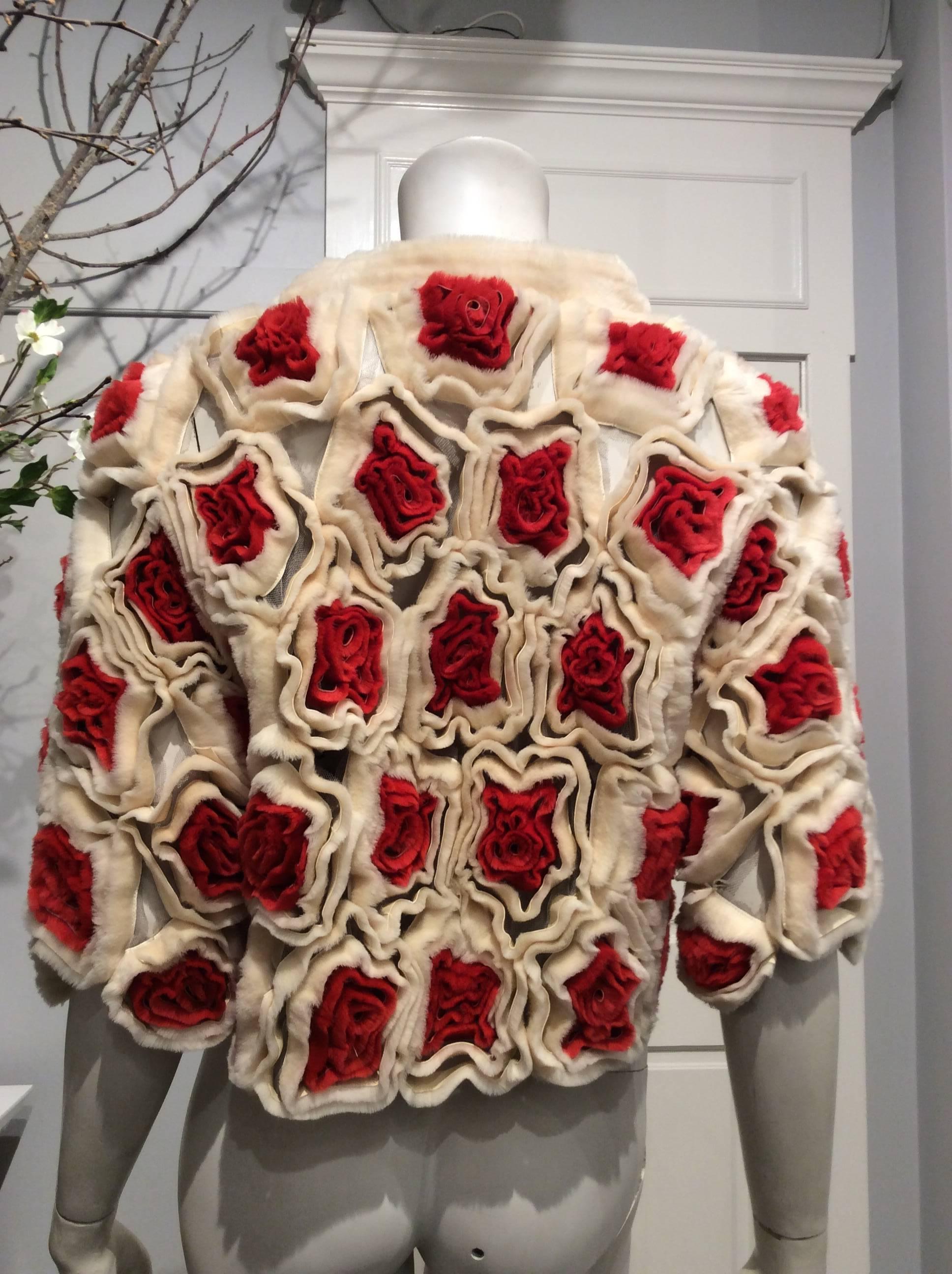 Strips of camel and red fur form distinctive flowers that are sewn on individual ivory tulle pieces like an airy patchwork and pieced together to create a most unique piece. The waist high jacket has a hidden hook closure and elbow length sleeves.

