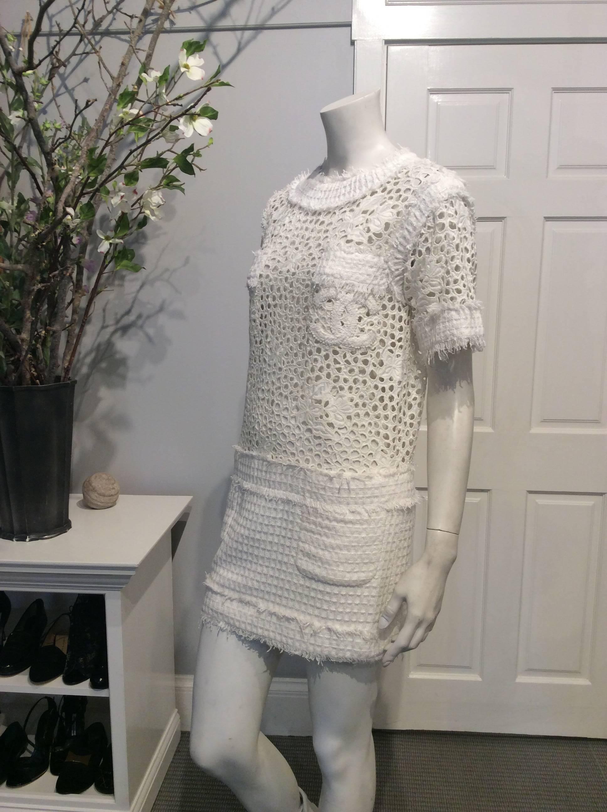 Off white Chanel dress in Sz 34 (Us 2). The top and short sleeves are made of heavy unlined lace. Two small lace front pockets cover the breast area and one of the pockets is embroidered with two iconic CC. The short skirt is in a waffle fabric and