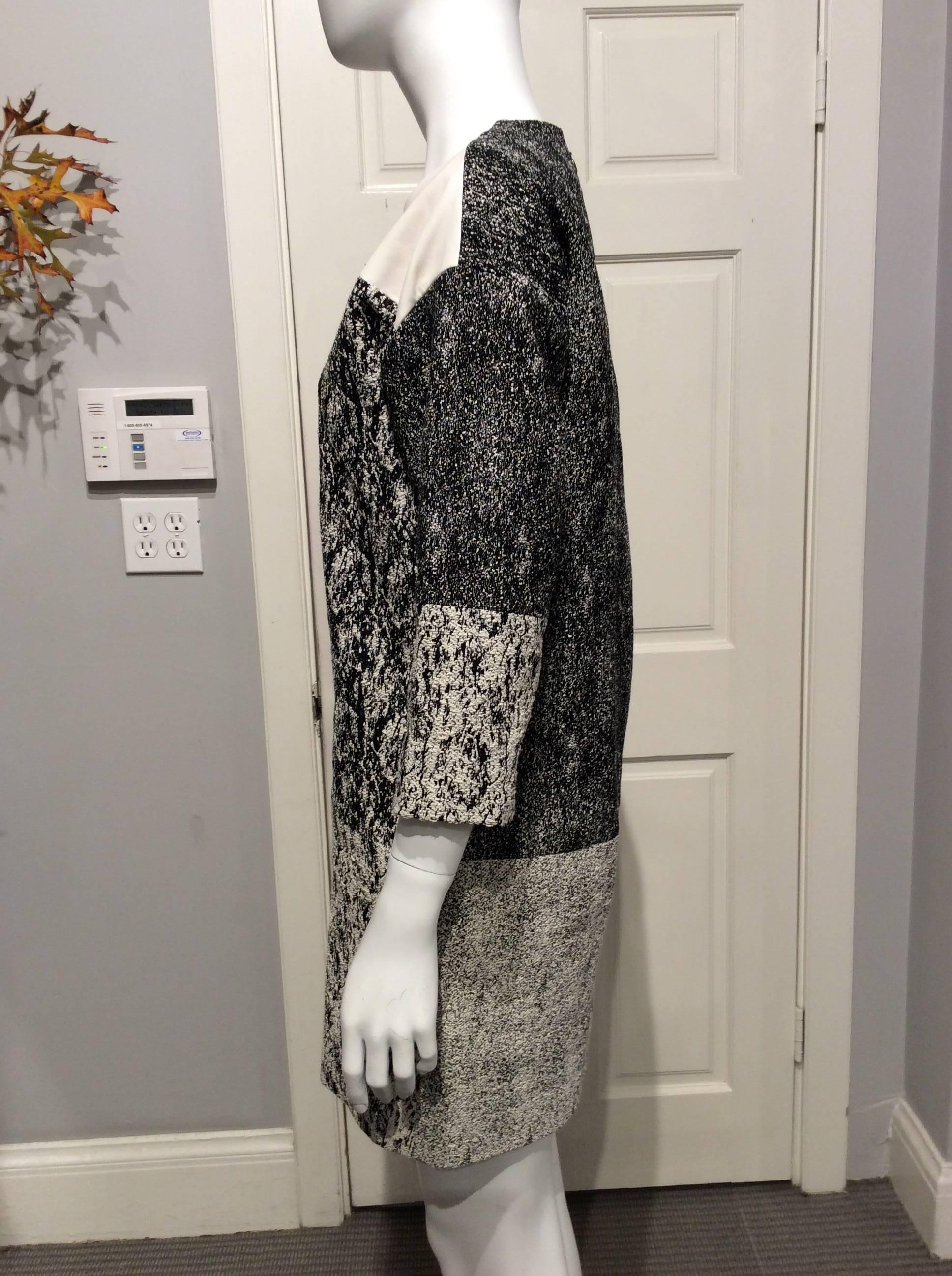 Black and cream patterned Celine dress accentuated at the neck and upper sleeves by ivory colored leather panels. The dress is slightly tapered with drop shoulders and 3/4 sleeves. It has two seam pockets.