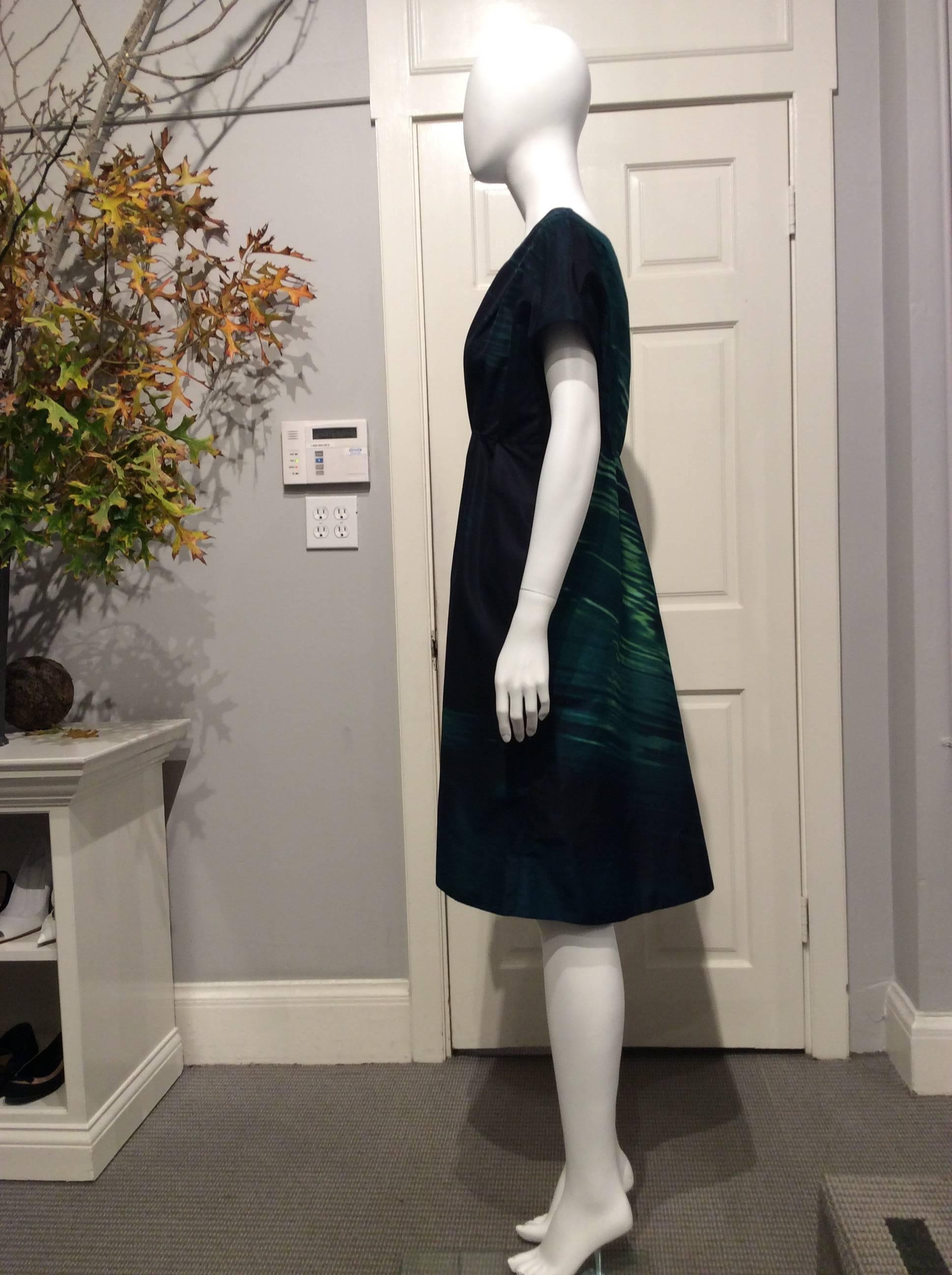 Marni silk dress with drop shoulder cap sleeves. The high waisted skirt is attached by a seam under the bust line with a few soft pleats. The way the eye catching abstract emerald green and blue black print is positioned gives it a very slimming