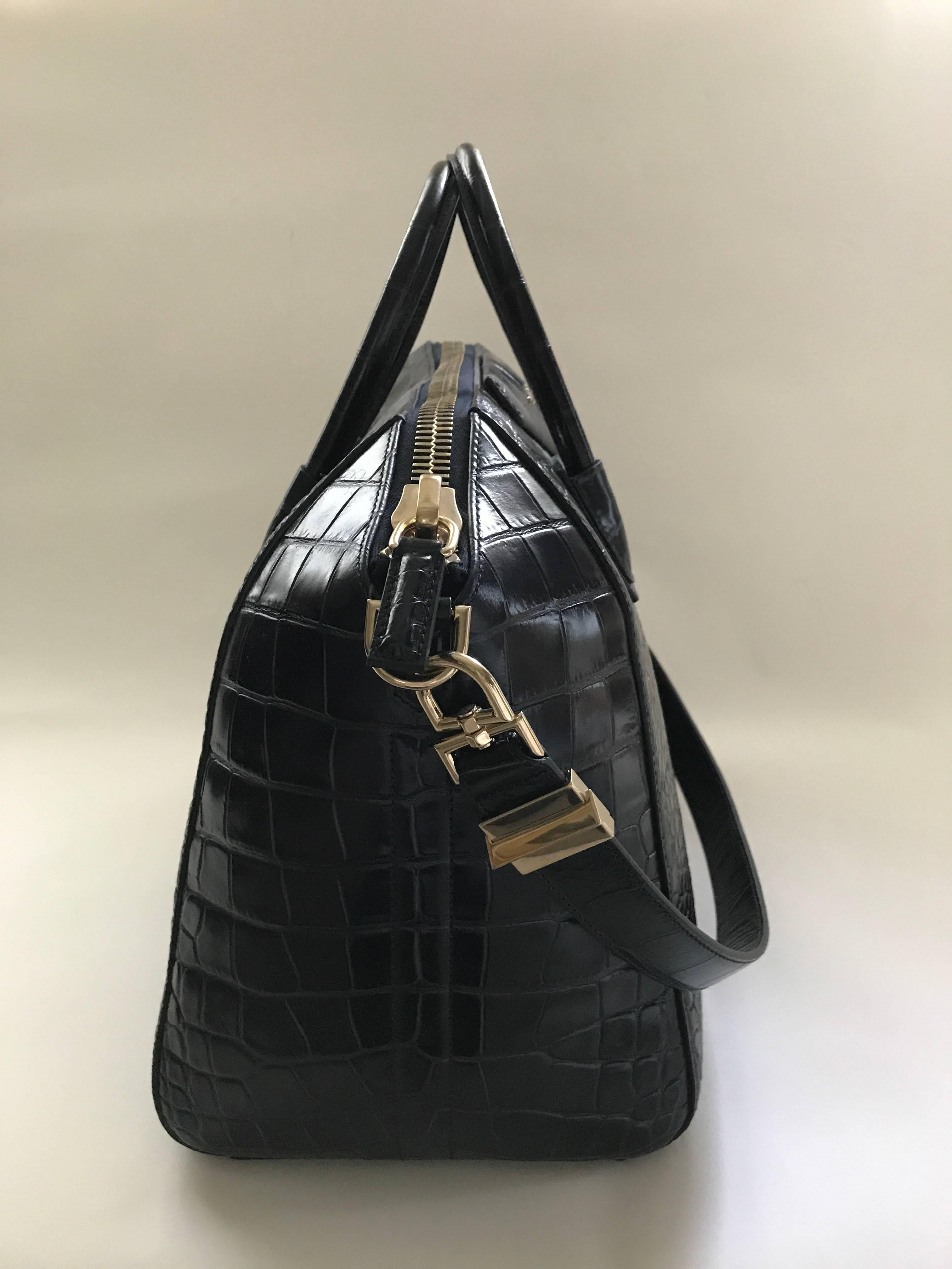 Givenchy large midnight blue Antigona bag in mock croc calf leather. Muted gold hardware, two top handles and a 29in x 1in shoulder strap. Black fabric lining with three wall pockets including a larger one with zipper.
Dimensions: H 12.5in / W 18in 