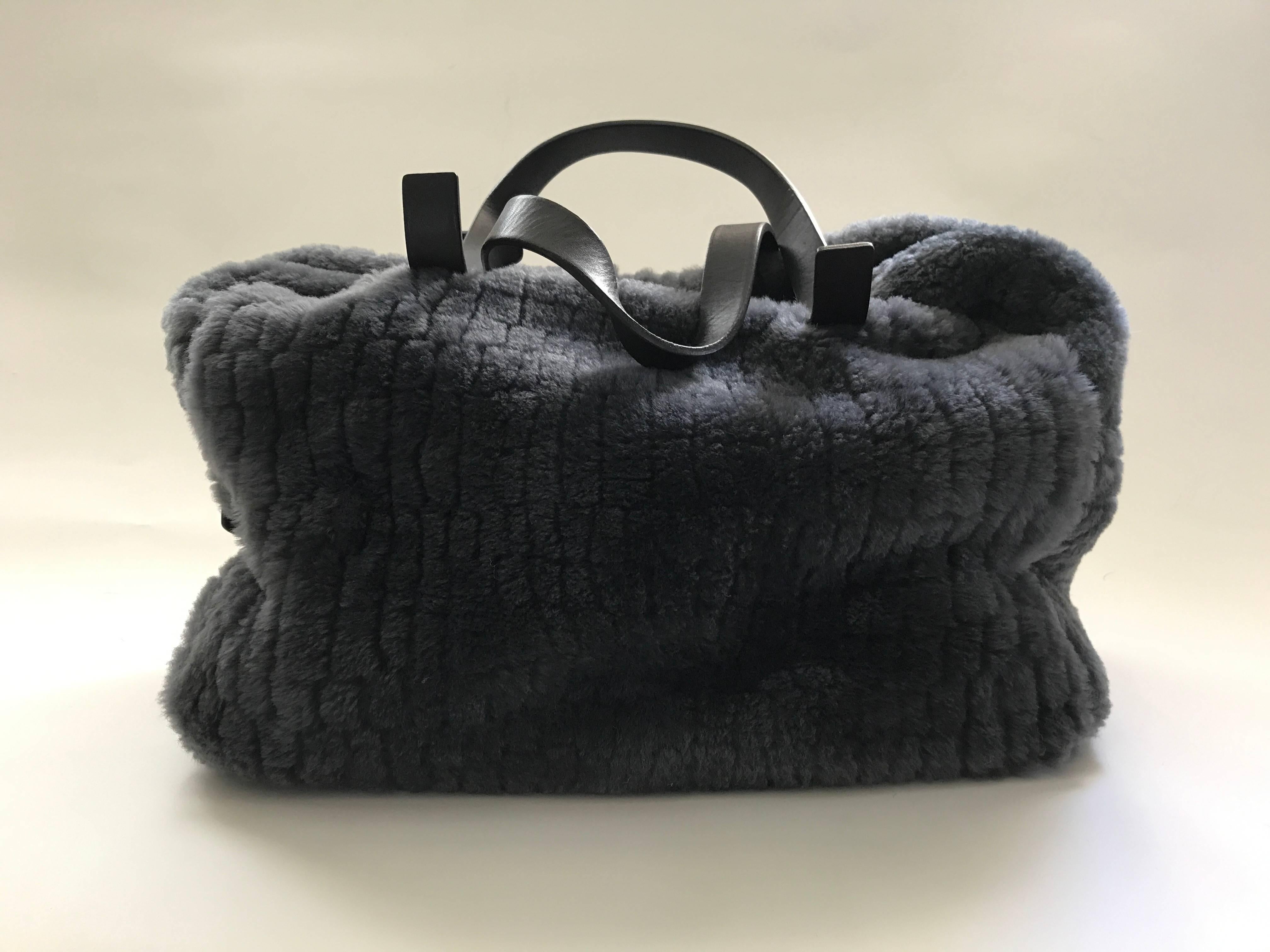 Pewter grey shearling bag in a mock alligator pattern with dark brown 17.5' double flat straps and dark brown leather trim and footed bottom. It closes with a 23' long silver colored zipper. Dark grey fabric lining with three wall pockets including
