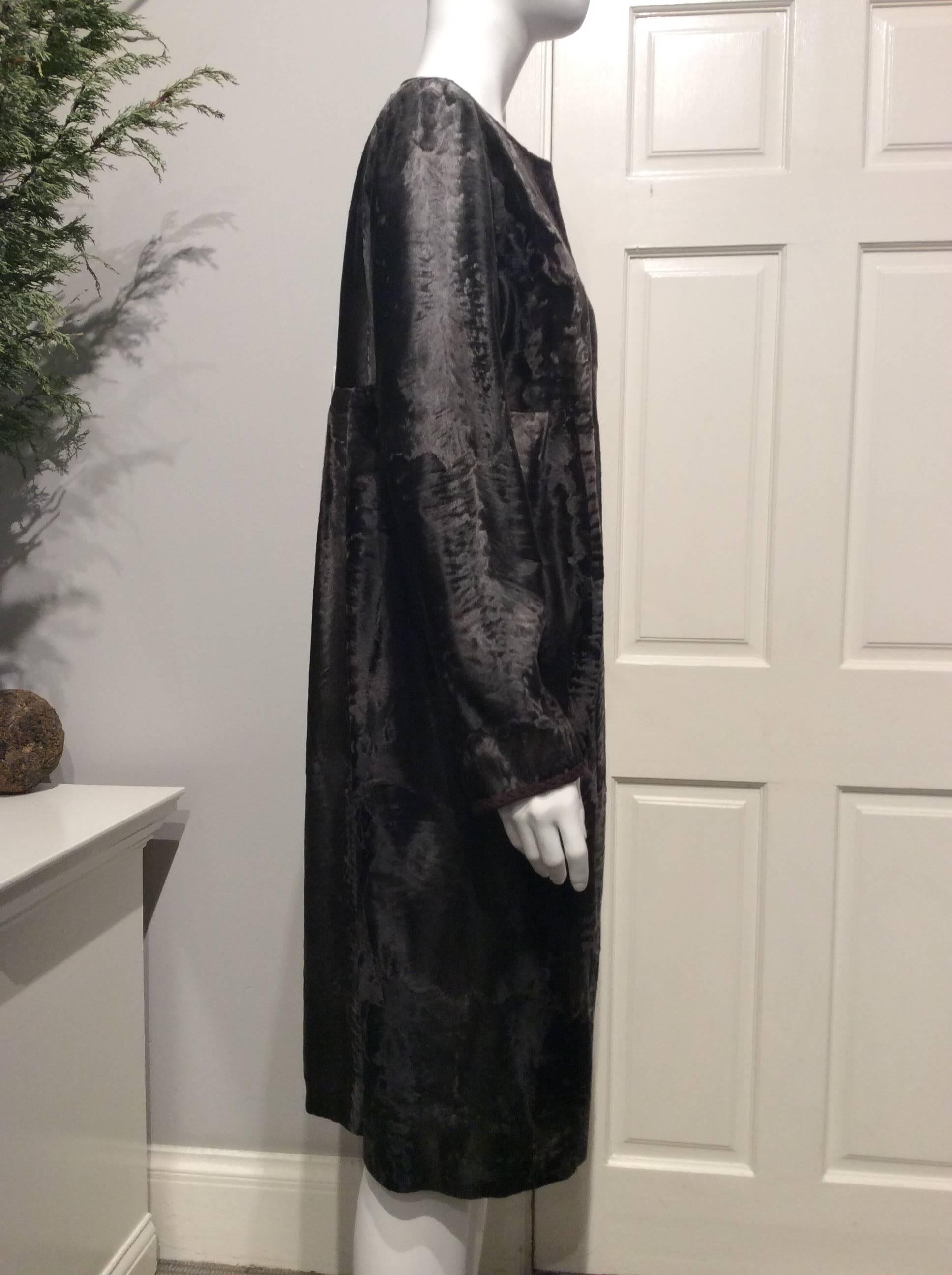 J. Mendel grey-brown Broadtail high waisted coat with four flat pleats in the front and back. It has two seam pockets. It has a trim of dark brown sheared mink inside. This coat closes with five fabric covered oversized snaps. Inside, displays an