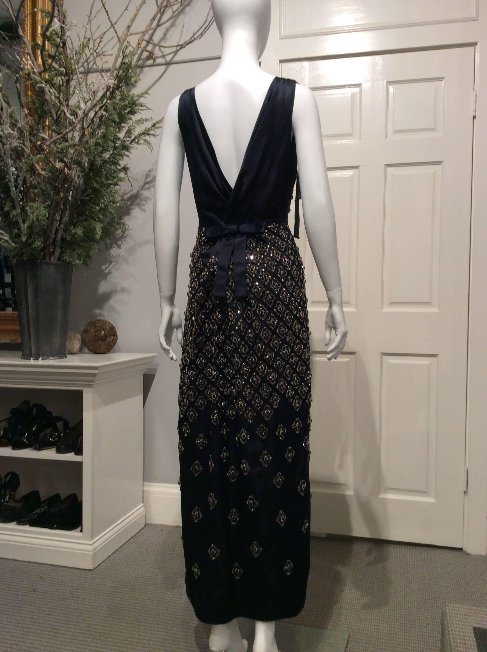 Stunning midnight blue satin gown covered in jewel embroidery in white and black rhinestones, silver glass beads and metallic copper thread. It has a waist deep v-neck back highlighted in the back with a flat bow. All seams are unfinished. It has a