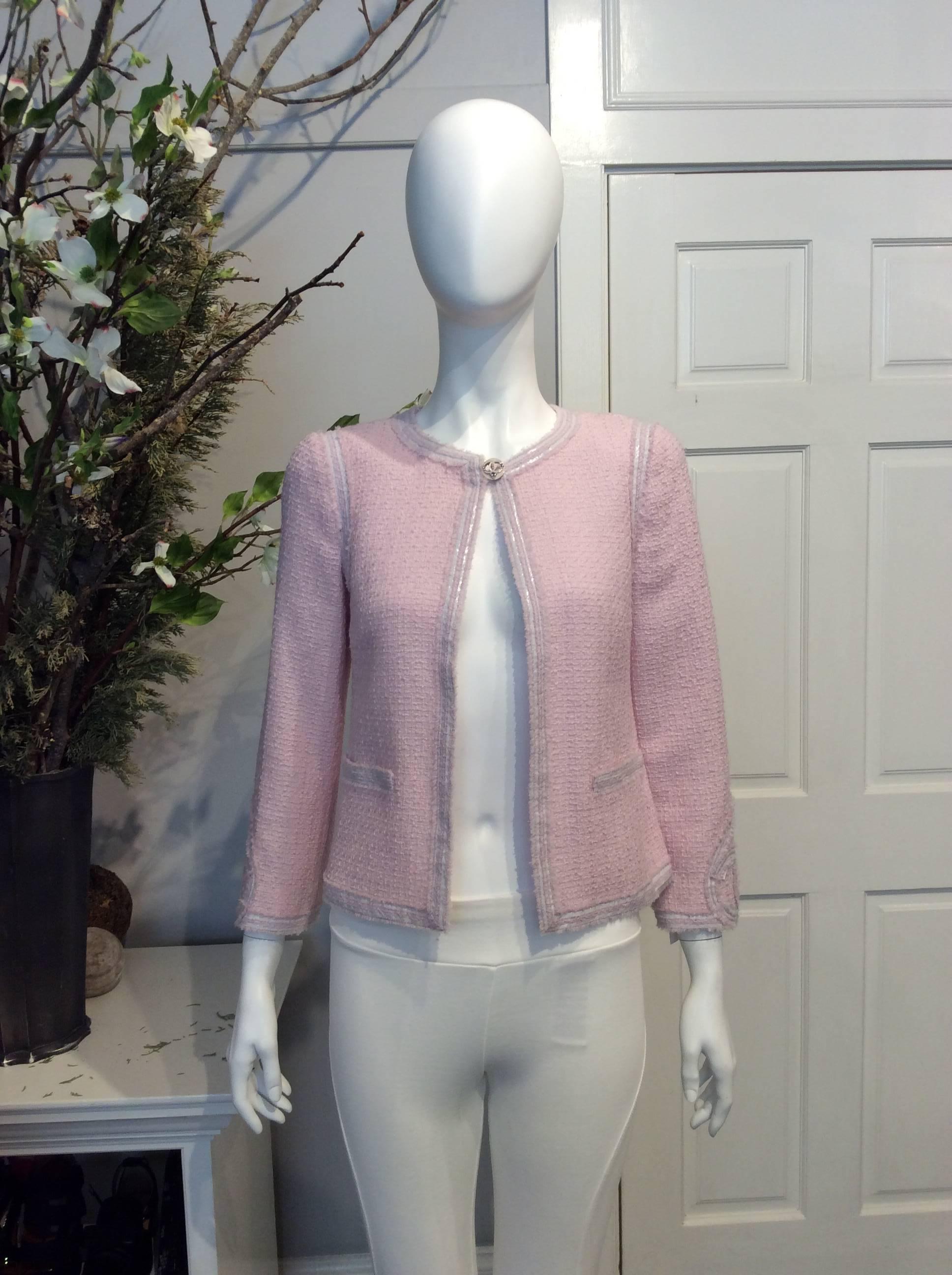Chanel light pink tweed jacket with white nylon trim throughout. Dual tweed pockets at front. Light pink and white Chanel heart accents on each sleeve and back collar. One light pink gripoix and silver baubled Chanel heart button closure at collar.