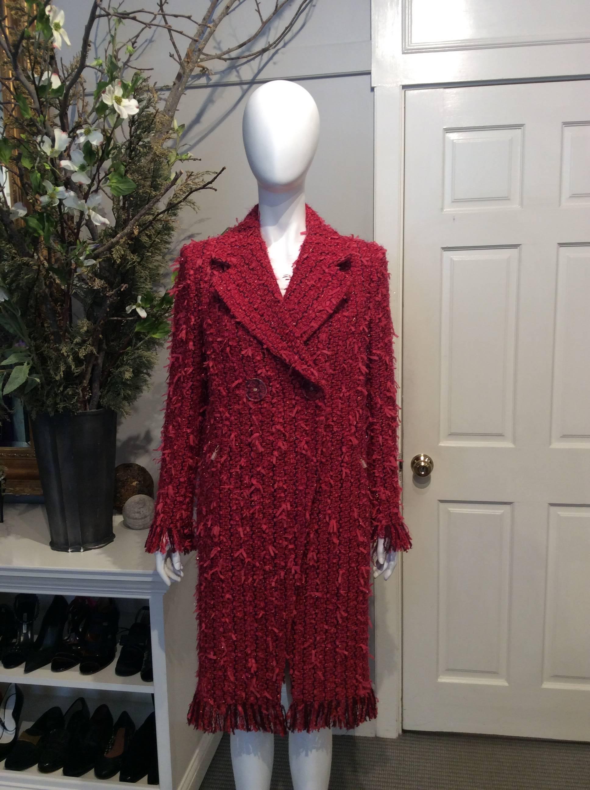 Chanel raspberry, red, and plum full-length double-breasted Fantasy Tweed coat from the pre-Fall 2017 collection. Ribboned accents throughout tweed. Fringe on sleeves and at bottom of coat. Dual pockets with gold zippers. Gold zipper on each sleeve.