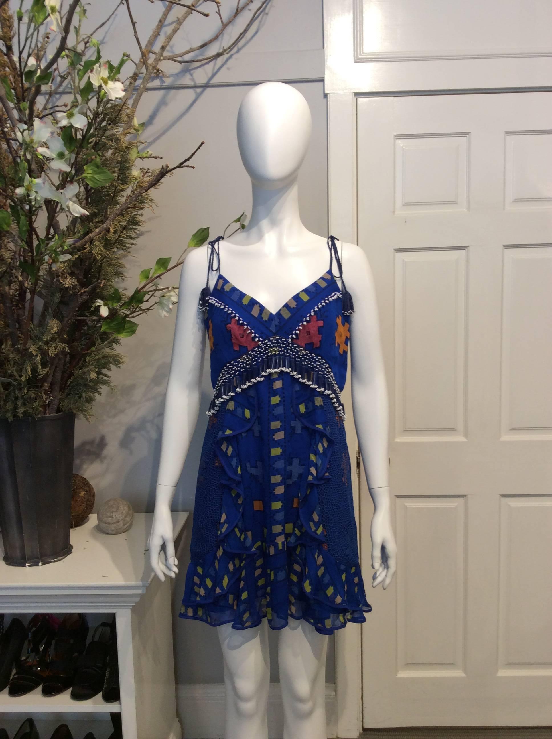 Royal Blue sleeveless dress from Istanbul-born designer, Zeynep Tosun. Drawstring straps with tassels. Tribal pattern with yellow, red, and orange. Blue and white tasseled beading on bust and looping around to the back of dress. Zipper and single