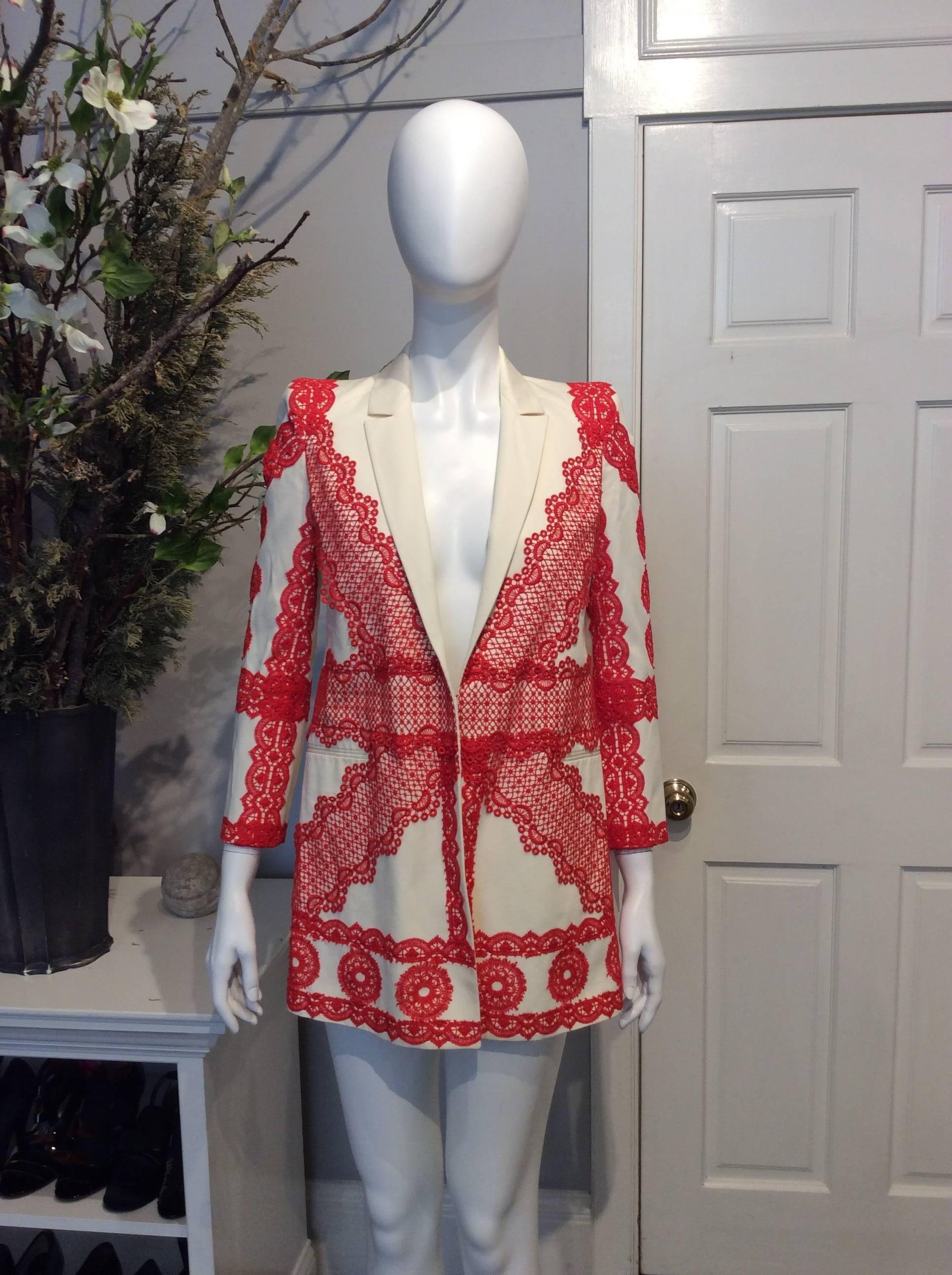 Ivory Givenchy jacket with deep coral lace and stitching throughout. Plunging neckline, vent in back of jacket. Single hook and eye closure at front. Dual pockets at front with two concealed pockets at interior. 

Sizing: Fr34, Us2

Fabric content: