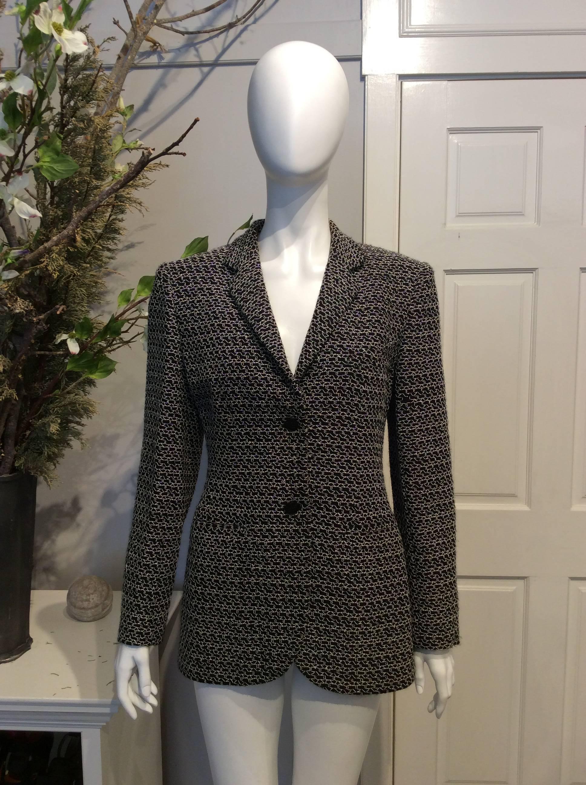 Chanel black tweed jacket with white woven, textured pattern throughout. Two black buttons at front of jacket. Single black button at each cuff. Black silk lining. Dual pockets. 

Sizing: Fr40, Us8

Fabric content: Wool, rayon, Nylon. Lining: Silk,
