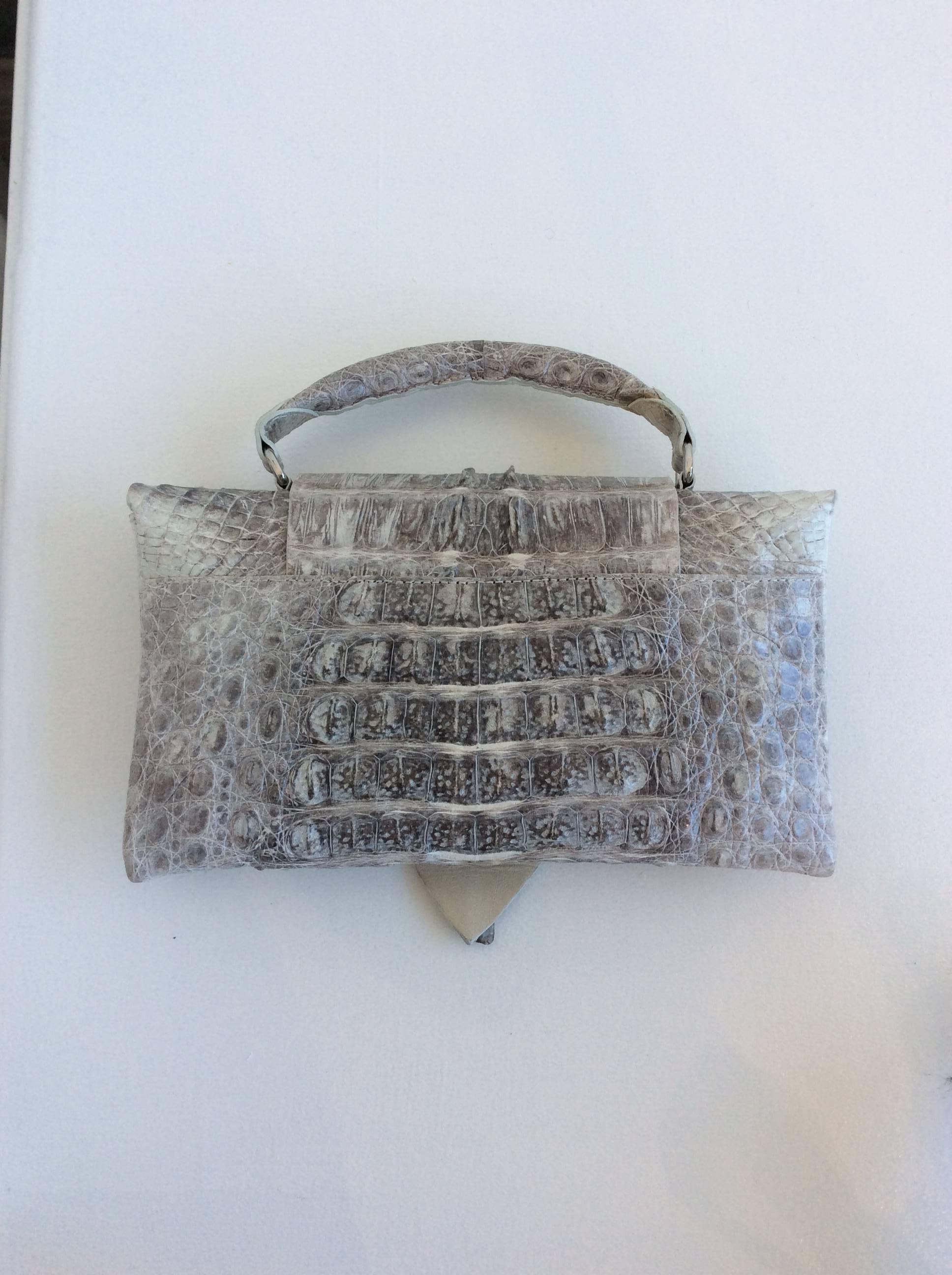 Genuine crocodile gray B. Romanek Rockstar clutch bag. Beige suede interior with zippered pouch at interior wall. Fold over magnetic closure at front. Crocodile drop handle at top. Estimated retail $2,195. Due to restrictions, this item cannot be