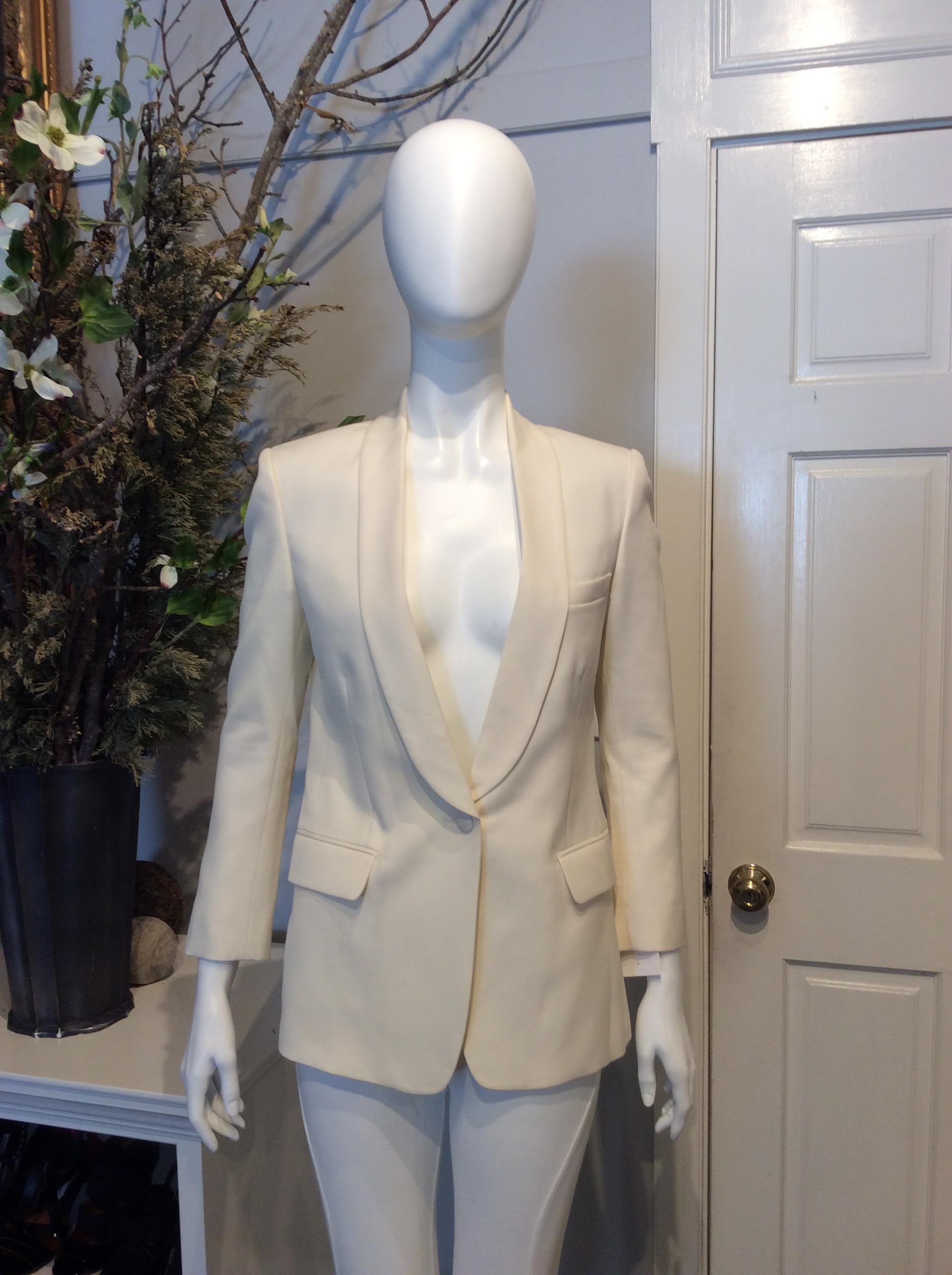 Ivory Balmain wool blazer. Tuxedo lapels. Single button closure at front. Dual pockets at front. Three concealed interior pockets. Chest pocket at front. Three buttons at each cuff. Vent at back. Includes an extra set of buttons.

Sizing: Fr34,