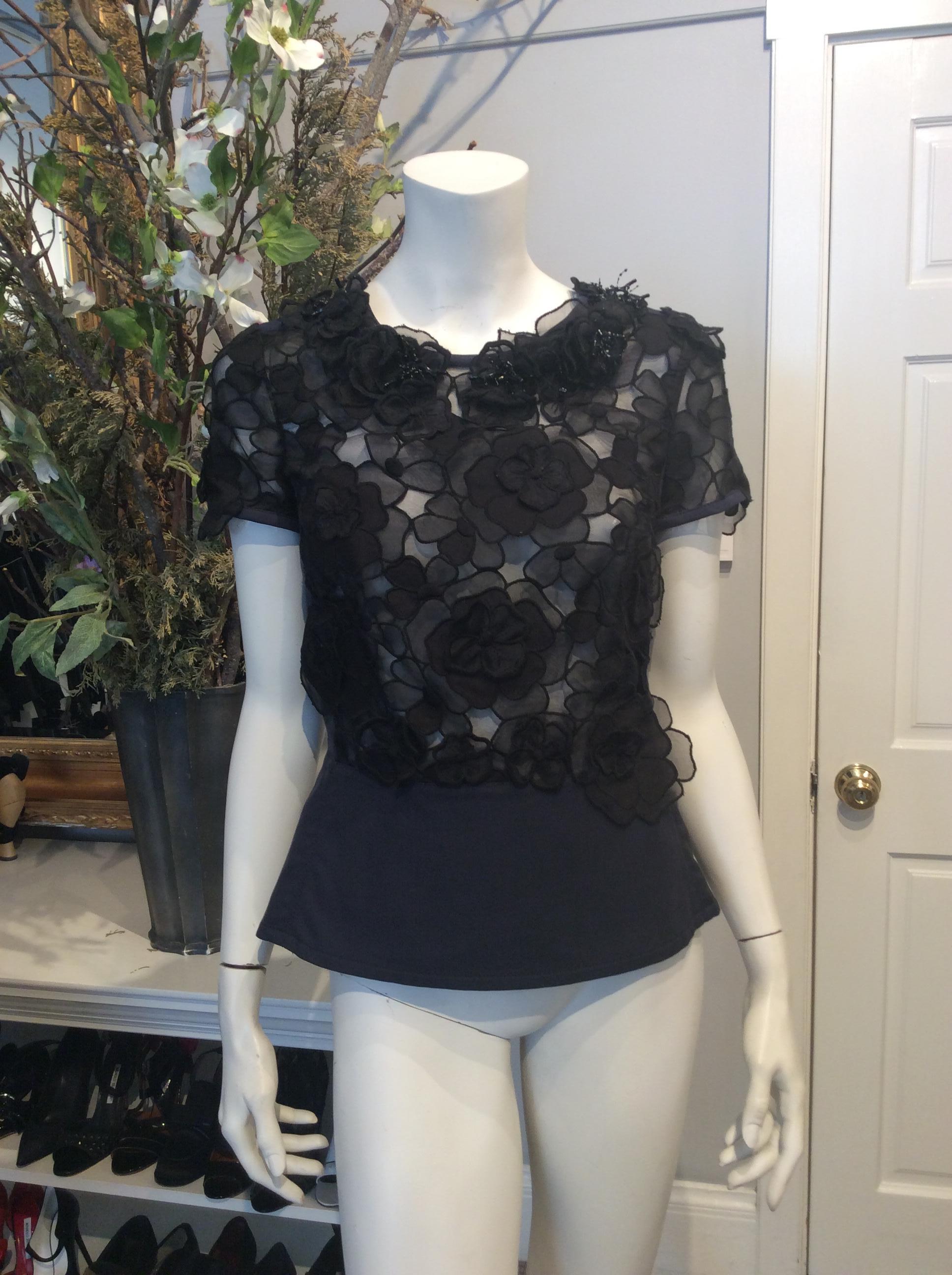 Black and navy Louis Vuitton fitted peplum top. Sheer black front with flowers throughout cap sleeves. Black coral shaped beading at neck. Navy peplum. Zippered closure along entire back of garment.

Sizing: Fr38, Us6

Fabric content: Cotton,