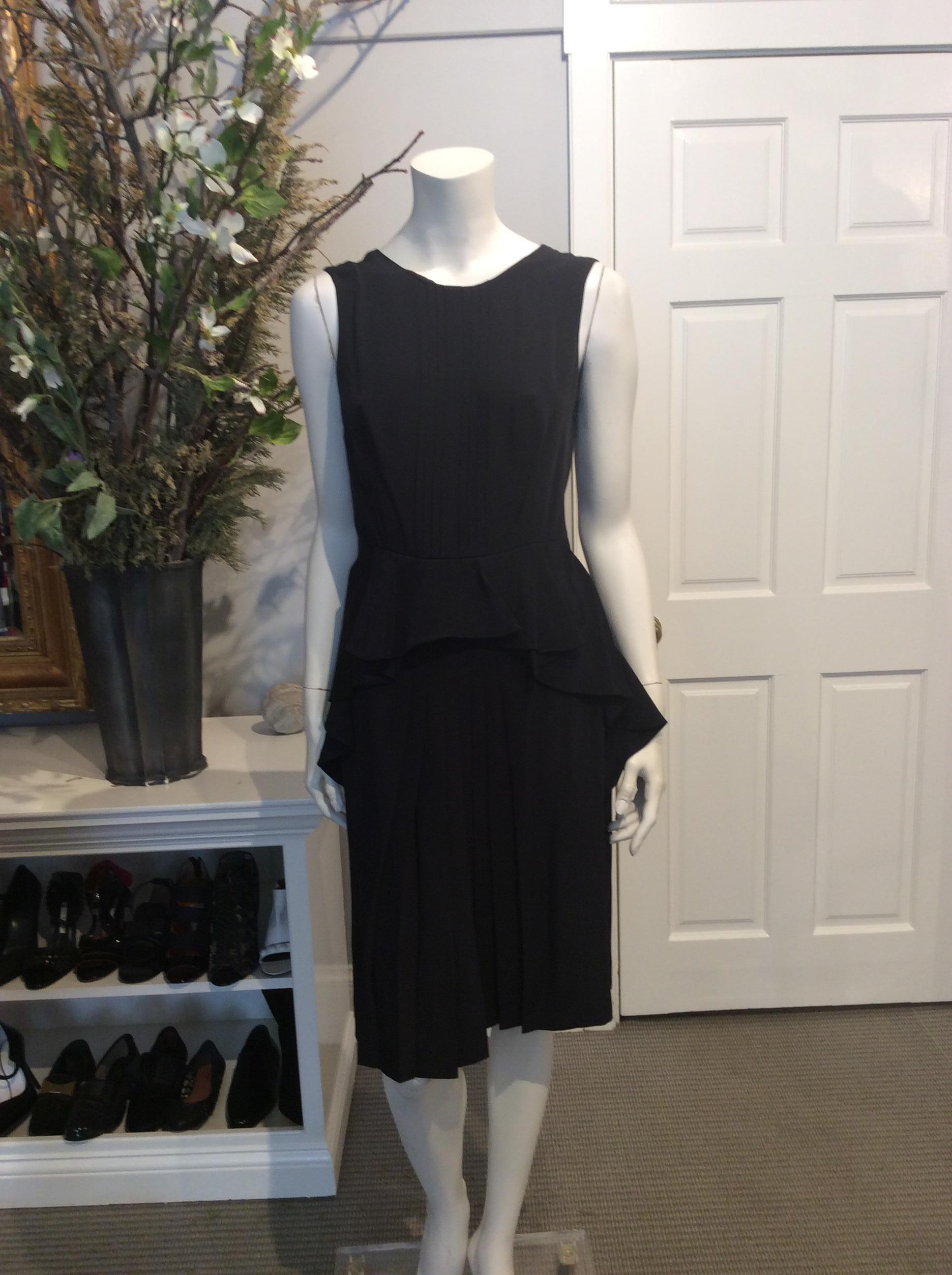 Black Prada silk dress with pleating down the front and skirt. Draped silk at hips. Open draping at upper back of dress. Zippered closure along the left hand side of garment with single hook and eye. Dress is new with tags.

Sizing: It42,