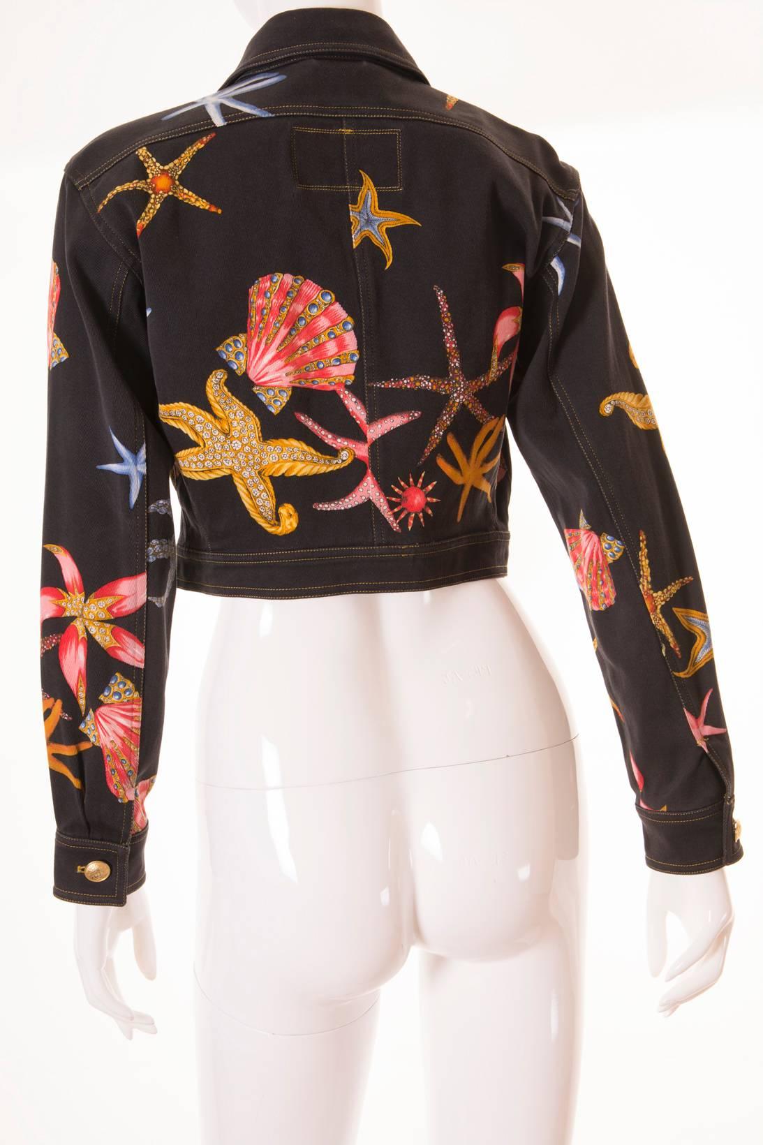 This Gianni Versace denim jacket was famously worn by Cindy Crawford on the runway.  Circa 1992. Charcoal denim offset with vibrant coral, gold, and grey-blue seashells, starfish and anemones.  Thick high quality denim.  Huge gold statement buttons.