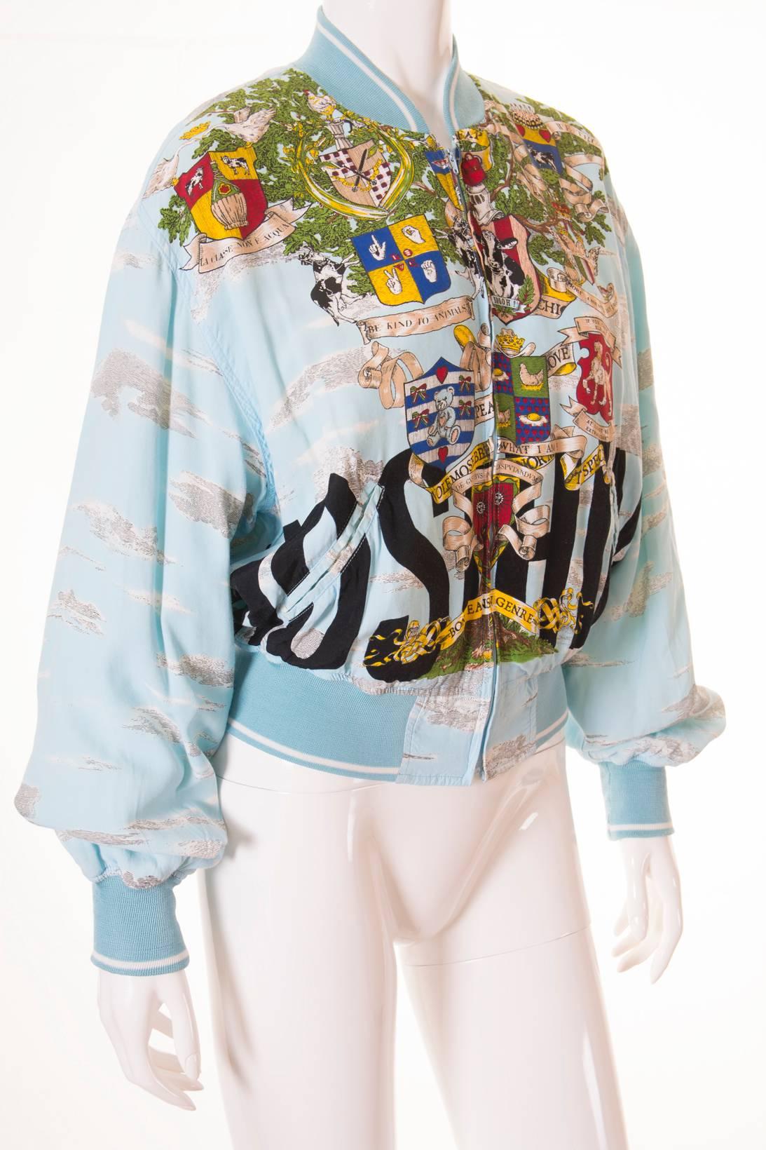 This bomber jacket by Moschino jeans features an incredibly detailed tree print and a huge Moschino logo emblazoned at both the front and the back.  Moschino slogans all over the jacket including “Be kind to animals”, “Volemossebene”, “More chickens