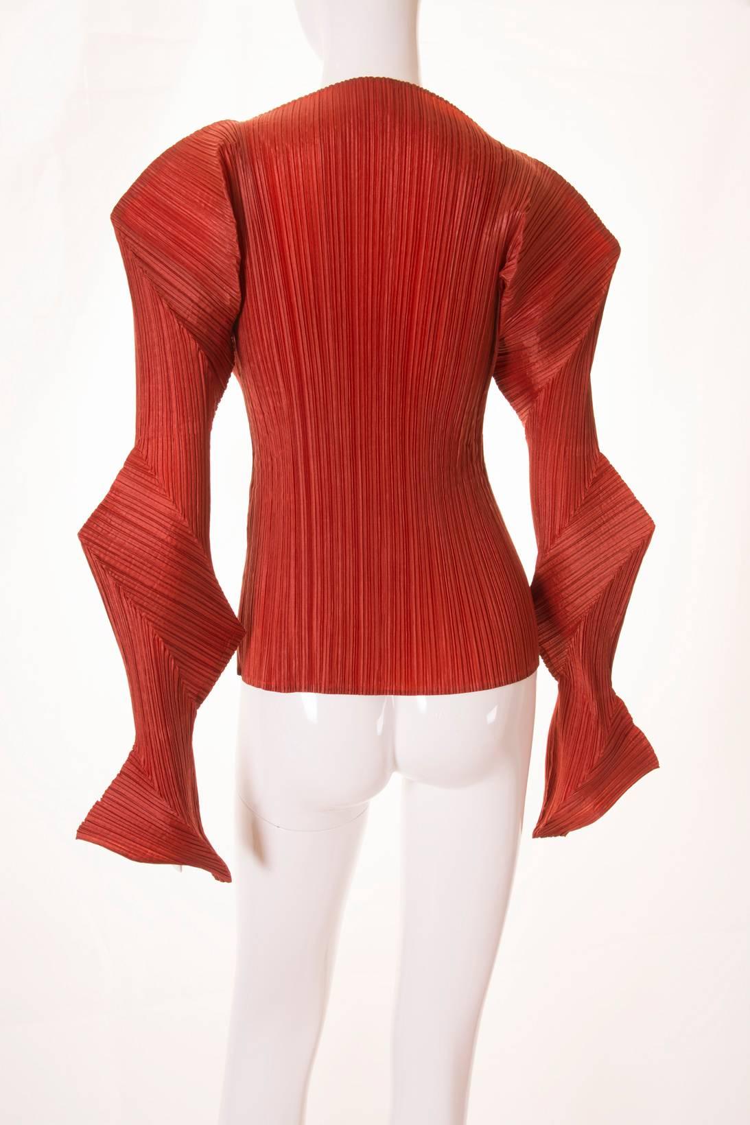 This breathtaking, rust coloured top by Issey Miyake is in his signature pleated fabric.  The design of the piece demonstrates his innovative and technology driven approach to fashion.  The sleeves are made up of separate panels with the pleats