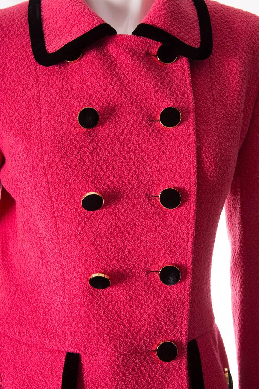 The classic Chanel suit is a wardrobe staple and this particular piece is a shining example.  Double breasted, vibrant pink Chanel suit with velvet trim and velvet buttons.  Wool fabric.  Circa 1996.

This piece has kept beautifully and is in