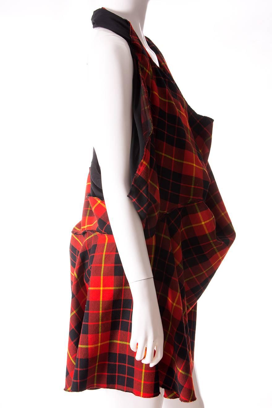 Dress designed by Junya Watanabe for Comme Des Garcons 2011 collection.  The outer layer is made of a red tartan wool fabric, and there is an inside layer of sheer polyester.  Halter neck with a low back and plunging front.  The style of the dress