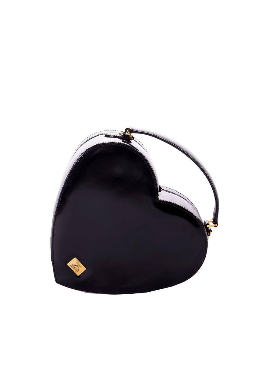 The perfect heart shaped box bag by Moschino in black patent leather.  This bag has a small handle at the top, but also has a detachable strap attached so the bag can be worn over the shoulder as well.  Clasp closure.  Redwall plaque at the back of