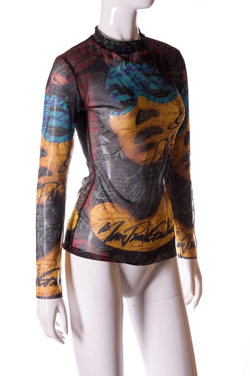 Sheer top by Jean Paul Gaultier with an allover face print at the front and the back of the top.  Mock turtleneck.  Text all over saying “Jean Paul Gaultier”.  Raw edge hem at the bottom of the top and sleeves.  Circa 90s.  

Excellent vintage