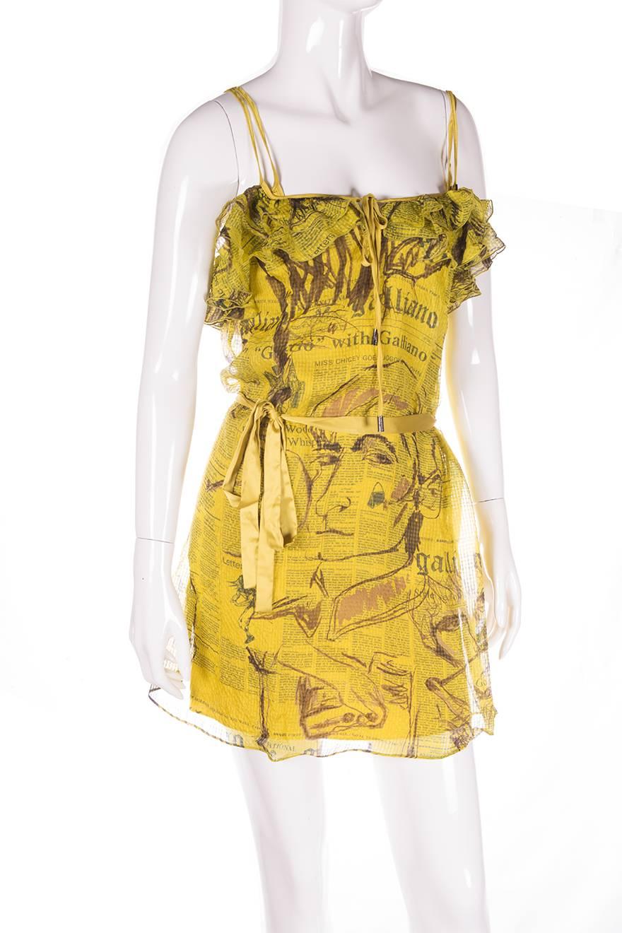 Dress by John Galliano in his iconic newspaper print.  This version has faces sketched over the newspaper.  The dress is made of one sheer, gauzy layer which is worn with a silk slip underneath.  Ruffled neckline.  Ribbon sash belt.  Dress can be