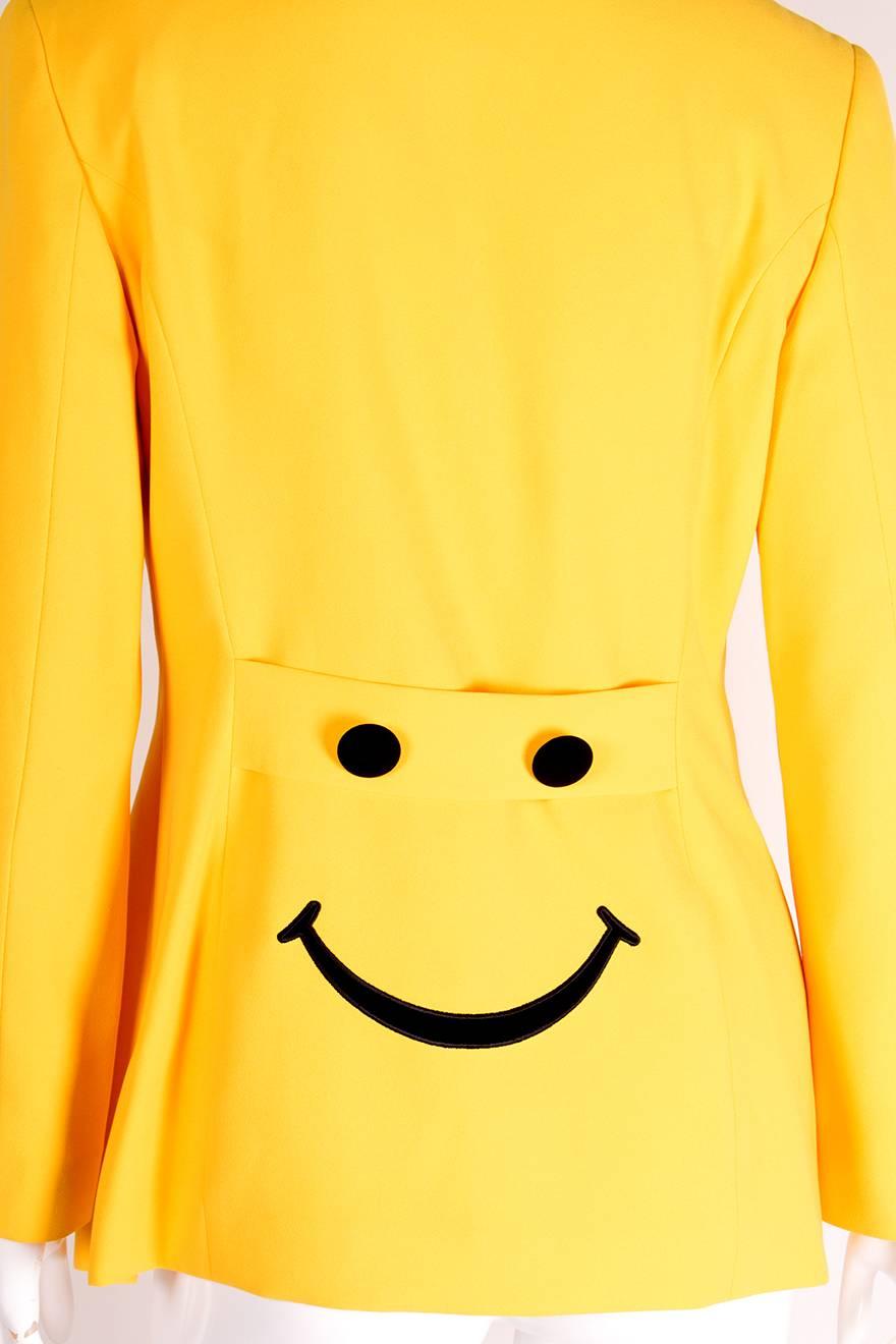 Iconic Moschino. Single breasted blazer by Moschino Jeans in a bold shade of yellow with contrast black buttons.  The back of the jacket has two black buttons and an embroidered smiling mouth which make a smiley face.  Circa 90s.

Marked size: No