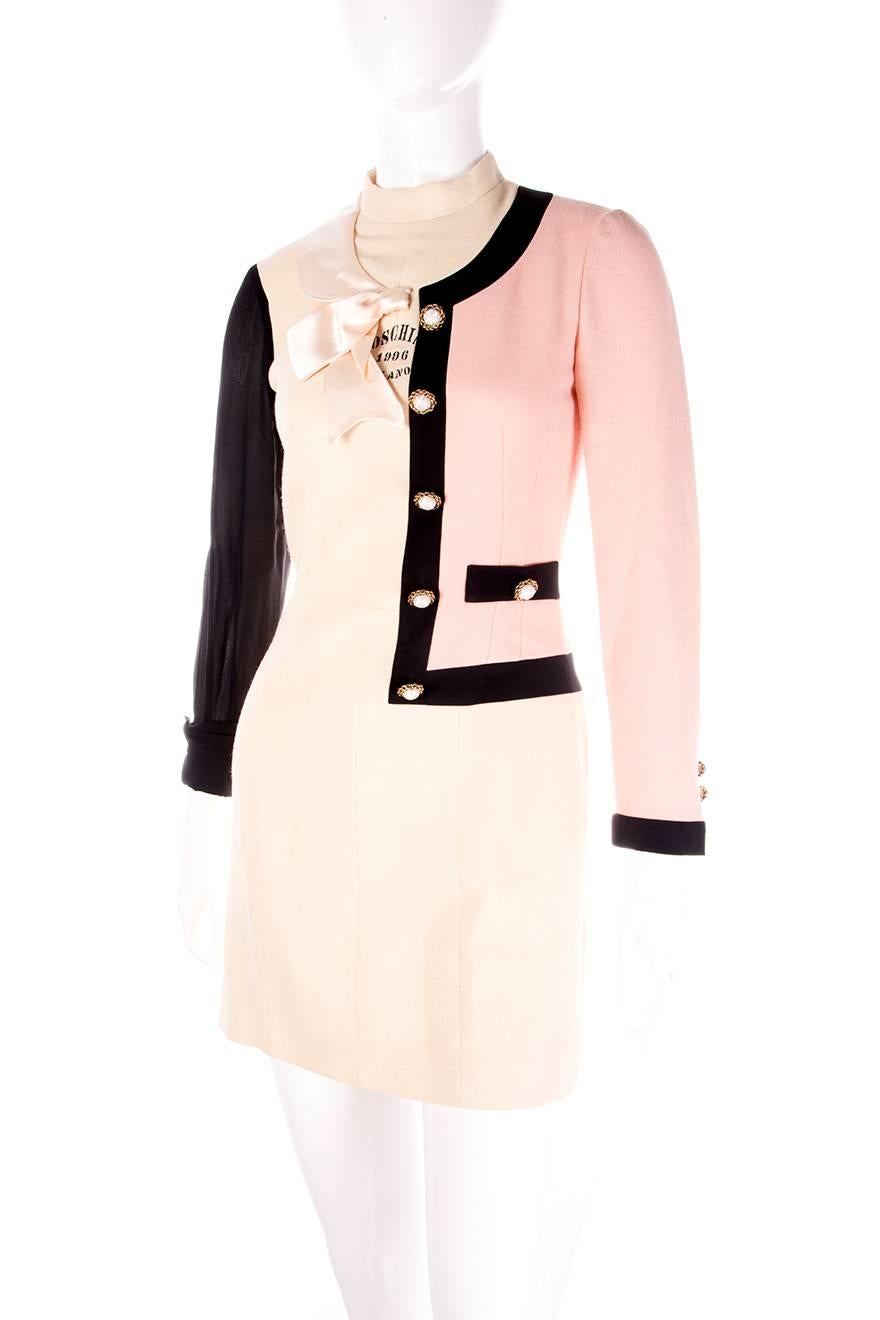 Rare dress by Moschino Cheap and Chic.  One half of the dress features a Chanel style jacket, and the other has a sheer sleeve and a ribbon at the neckline.  Circa 1996.

Marked size: 40 (IT)
To fit: S

Chest: 44 cm
Waist: 34 cm
Length: 83