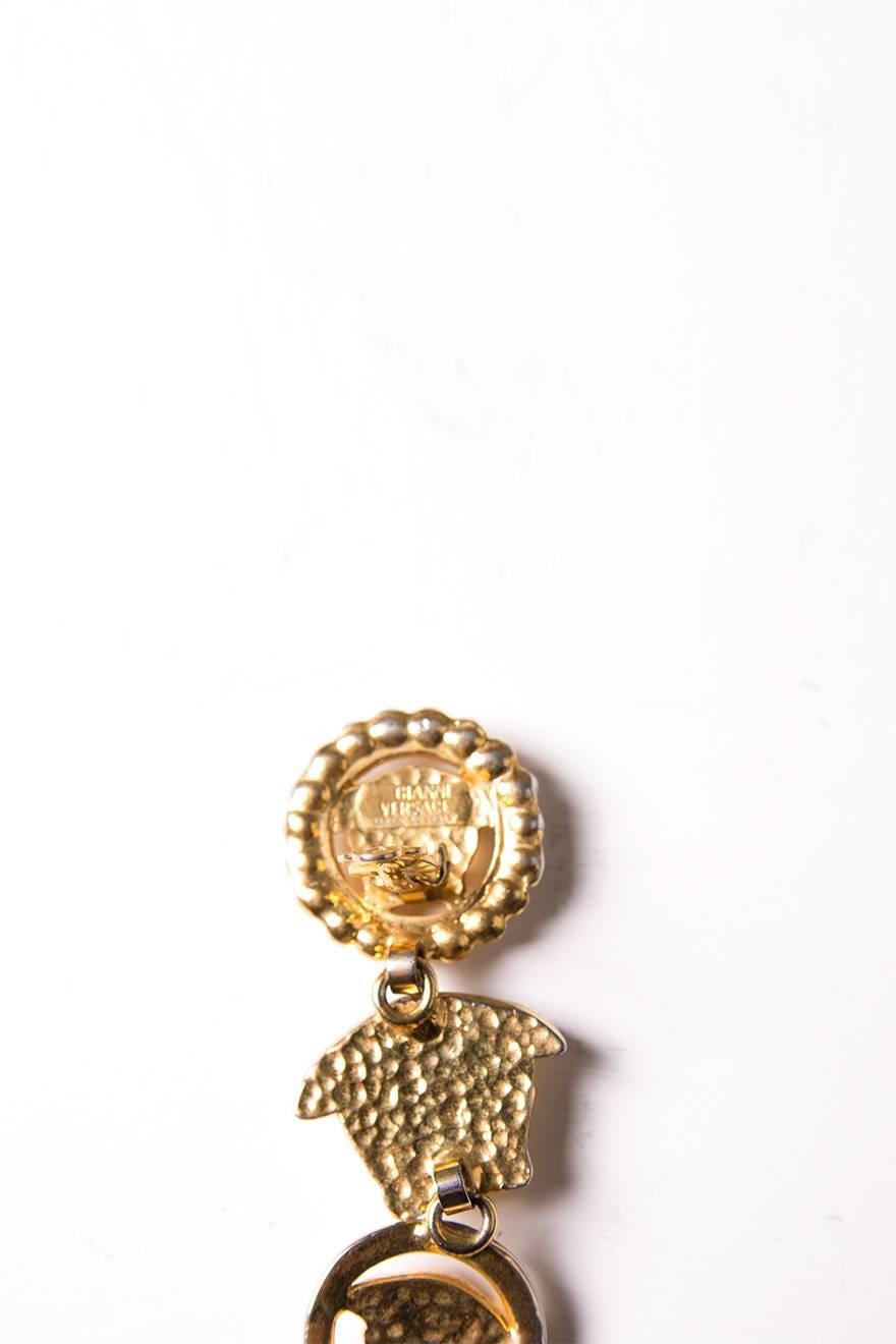 Gianni Versace clip on earrings with Medusa heads, surrounded by rhinestones. Circa 90s. 

Good vintage condition; two rhinestones missing on one of the earrings. Some minor overall wear to the coating.
Length: 2 cm
Width: 6.5 cm