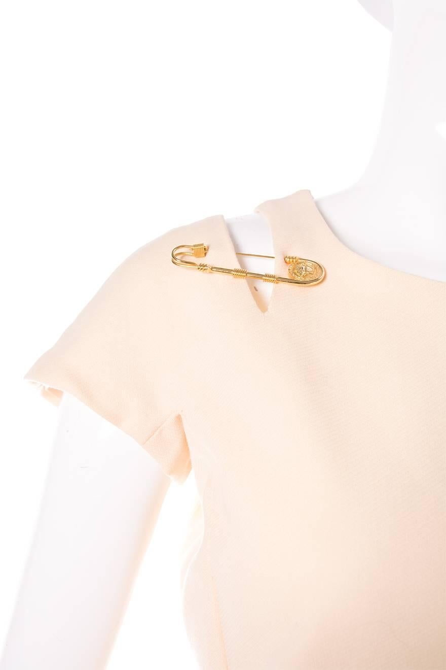 Classic shift dress in cream by Gianni Versace with a gold safety pin detail at the shoulder. This dress is an iconic piece of fashion history. Circa 90s. A similar version of this dress was recreated by Versus a few years back, this dress is the
