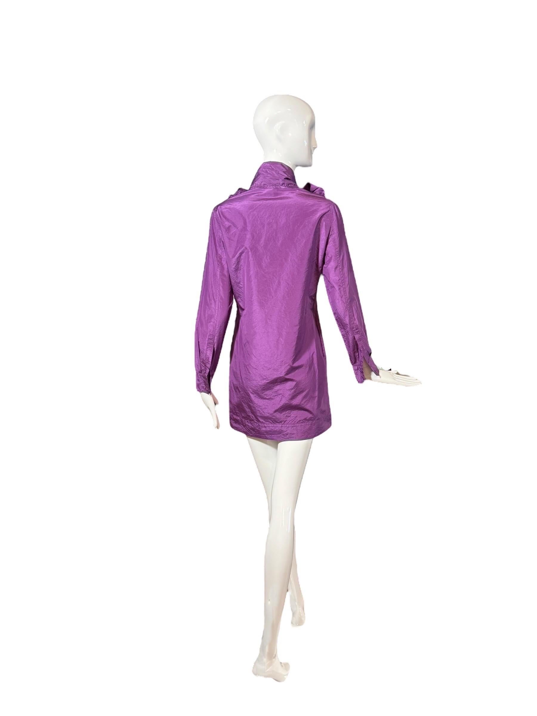 Cette mini robe violette Yves Saint Laurent Rive Gauche de la collection 2007 incarne la féminité moderne avec une touche dramatique. Fabrice dans un tissu lustré en soie mélangée, cette robe à manches longues est ornée d'un nœud surdimensionné à
