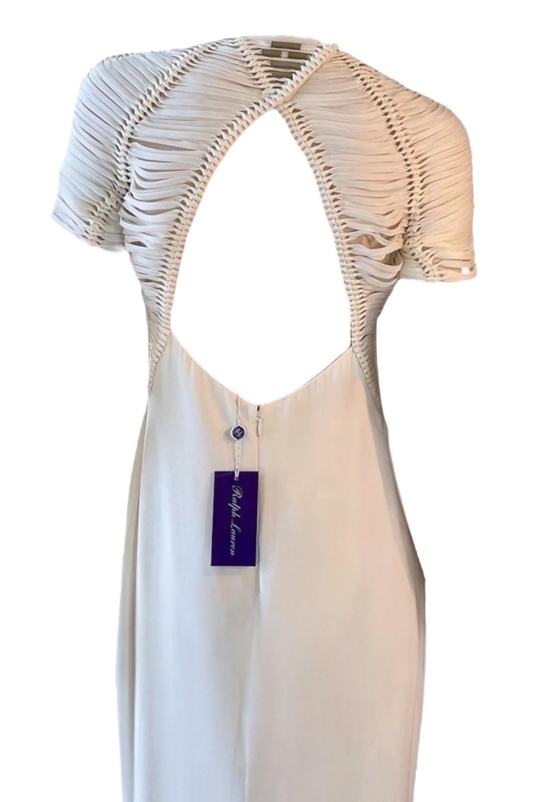 Questo splendido abito Ralph Lauren Purple Label, della collezione primavera 2015, mette in mostra la maestria dello stilista in fatto di linee pulite e dettagli raffinati. Realizzato in lussuosa seta bianca, questo abito lungo fino al pavimento