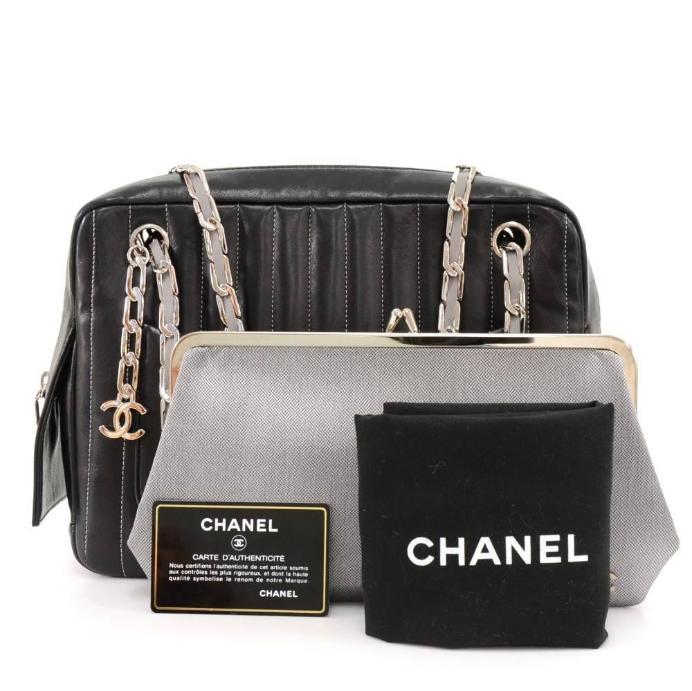 Chanel Mademoiselle shoulder bag in black vertical quilted leather. It has one open pocket on each side. Main access is secured with zipper. Inside is in gray fabric lining with 2 zipper and 1 removable wallet. Comfortably carried on shoulder with