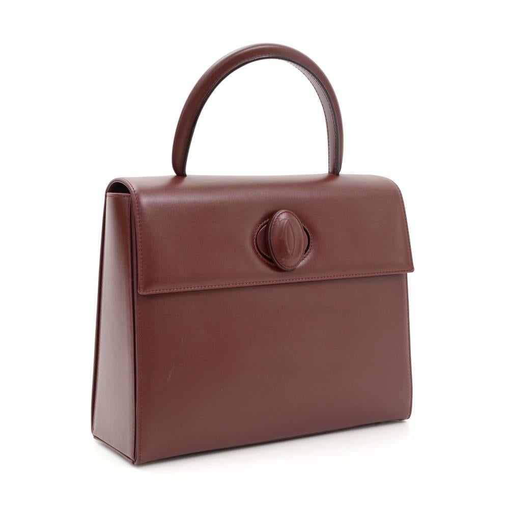 Catier Must Line hand bag in burgundy leather. It has twist lock on the front flap. Inside lining is in burgundy fabric with Cartier monogram and 2 pockets: 1 with zipper and 1 open. Very rare item to find. 

Made in: Italy
Serial Number: C
