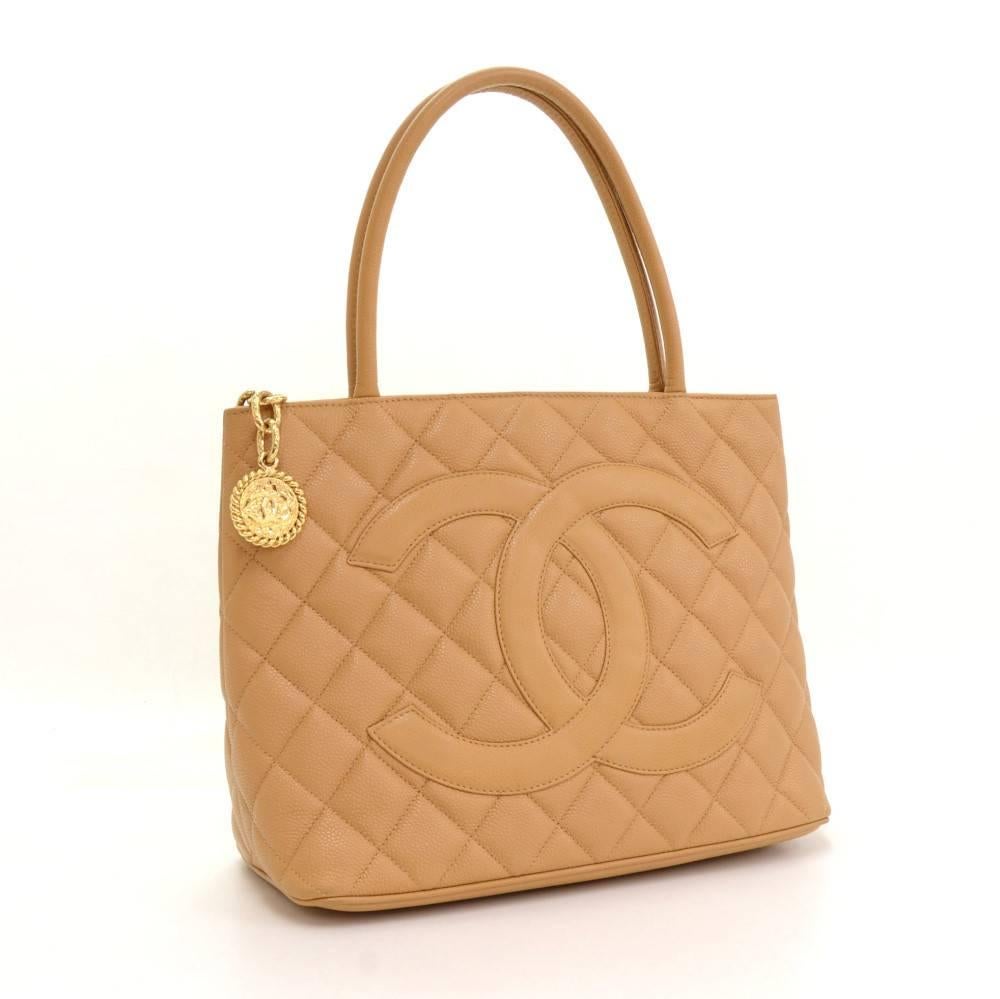 Chanel Revival tote in beige quilted caviar leather. Large CC stitched in front and slip in pocket on the back. Top secured with zipper closure and medallion on chain as zipper pull. Inside has leather lining and 2 pockets: 1 zipper and one open.