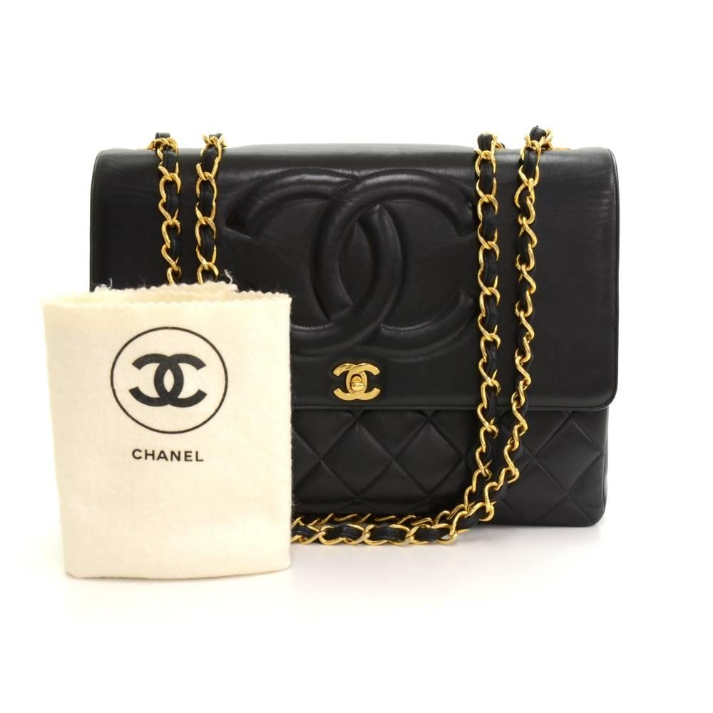 Chanel Maxi Jumbo in black quilted leather. It has flap top with famous large stitched CC on the flap. Outside on the back has 1 open side pocket. Inside has Chanel red leather lining and 2 pockets: 1 zipper and one open. Comfortably carried on