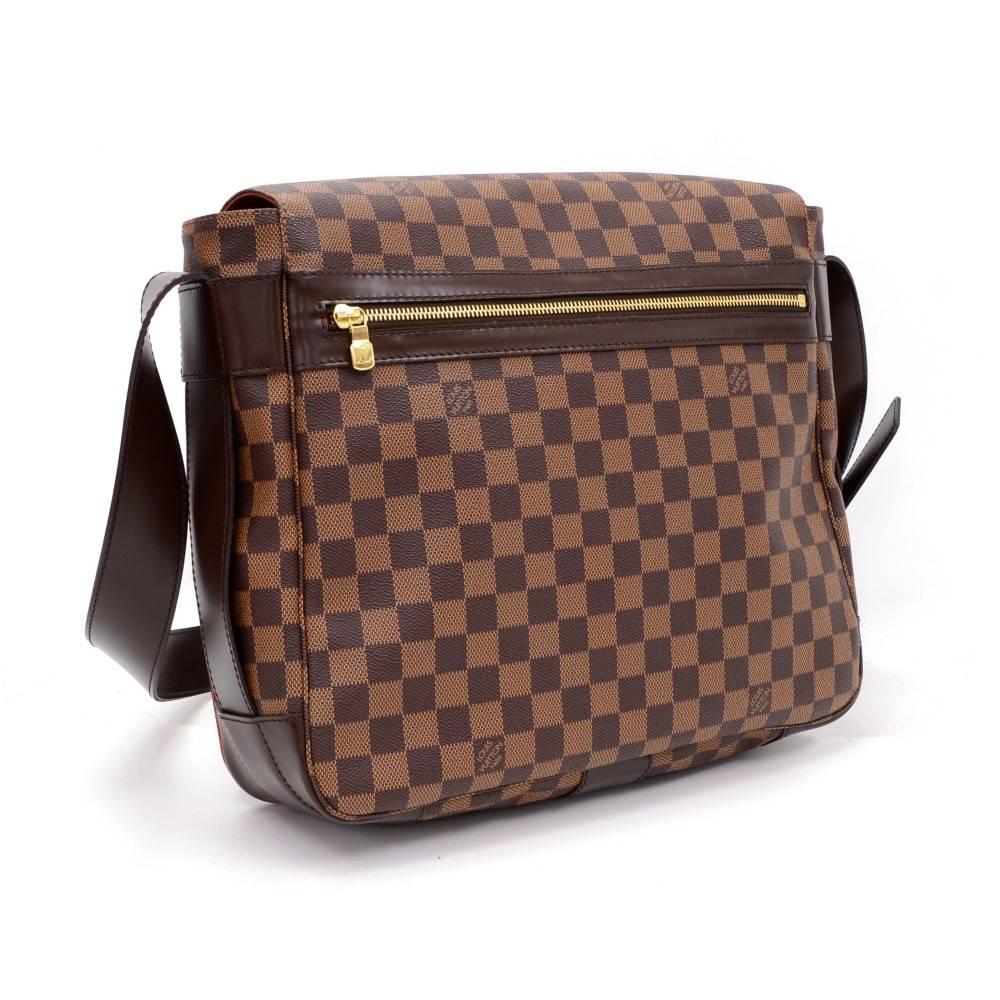 Louis Vuitton Bastille messenger bag in brown Damier canvas. It has secured with flap and 1 zipper slip pocket in the back. Inside is in red canvas lining with 2 exterior open pockets and 1 large interior open pocket. Comfortably carried on shoulder