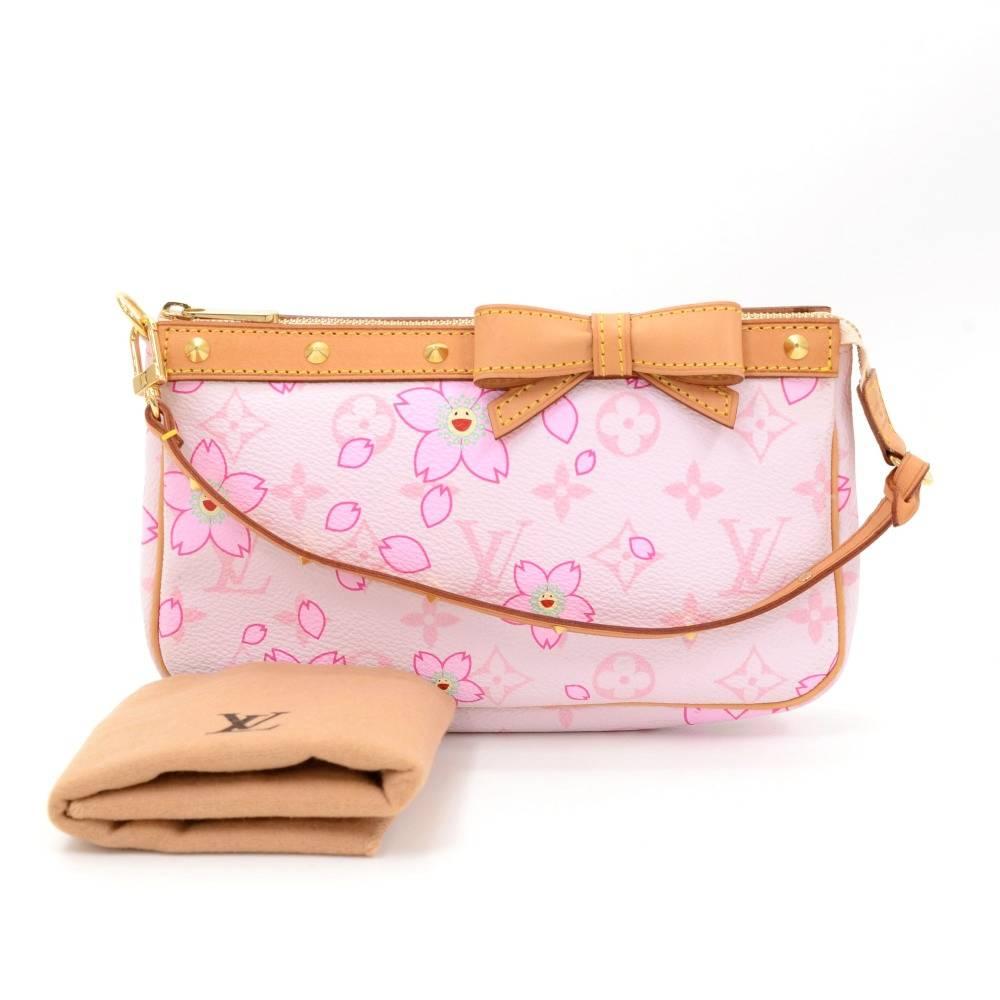 Louis Vuitton pochette accessories in monogram canvas with cherry blossom motif. It is a limited edition from the year 2003 designed by Murakami. It has a ribbon on the front and small gold tone studs on the leather handles. It stores beauty