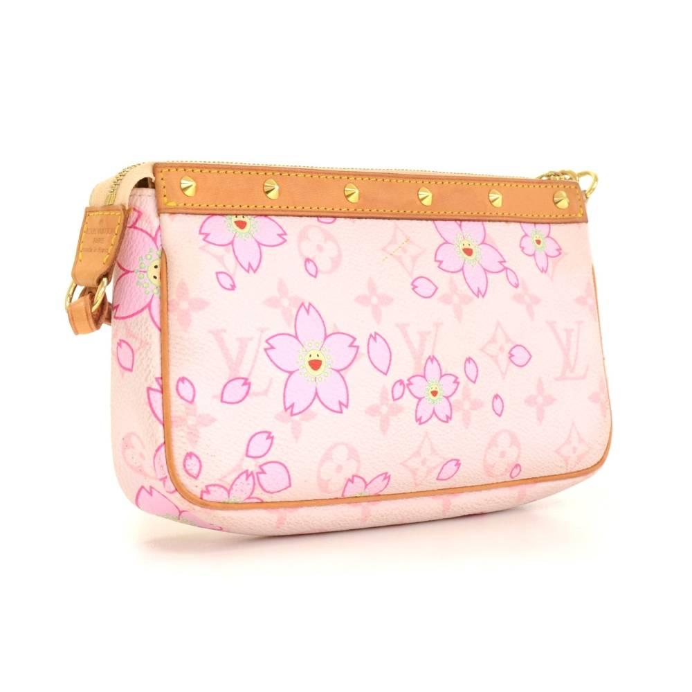 Louis Vuitton pochette accessories in monogram canvas with cherry blossom motif. It is a limited edition from the year 2003 designed by Murakami. It has a ribbon on the front and small gold tone studs on the leather handles. It stores beauty