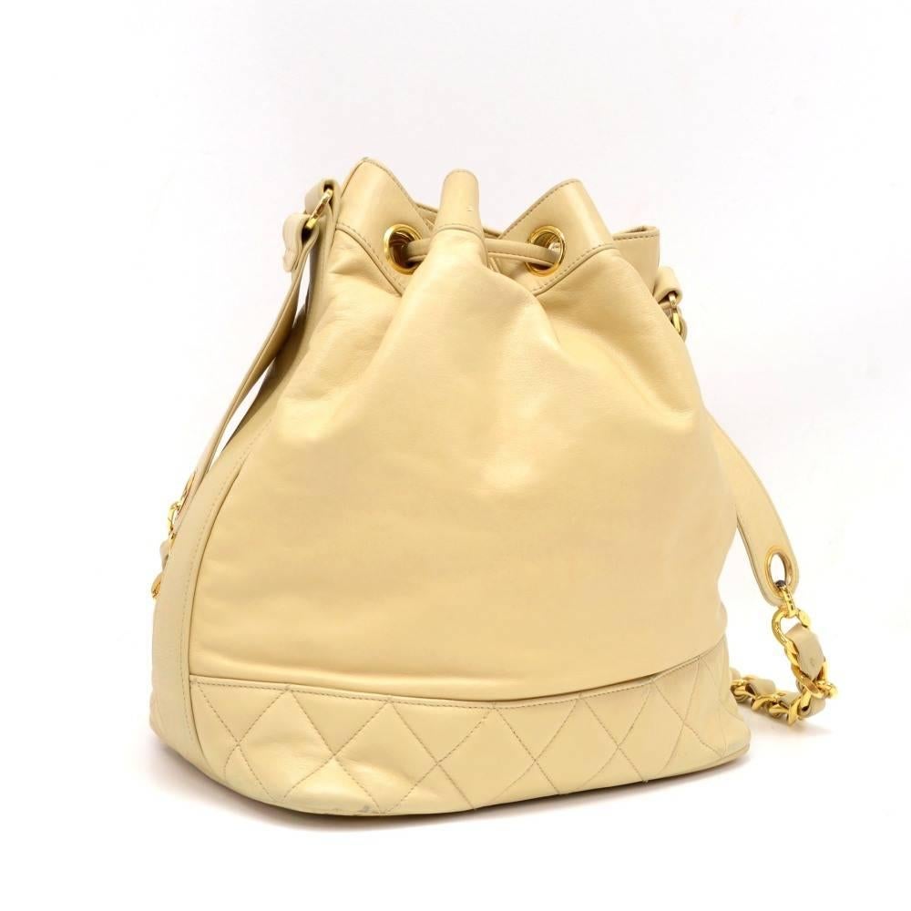 Chanel bucket shoulder bag in beige leather. It has stitched CC logo at the bottom. Main access has leather string closures. Inside has leather lining with 2 zipper pockets and attached pouch. Comfortably carried on shoulder.

Made in: Italy
Serial