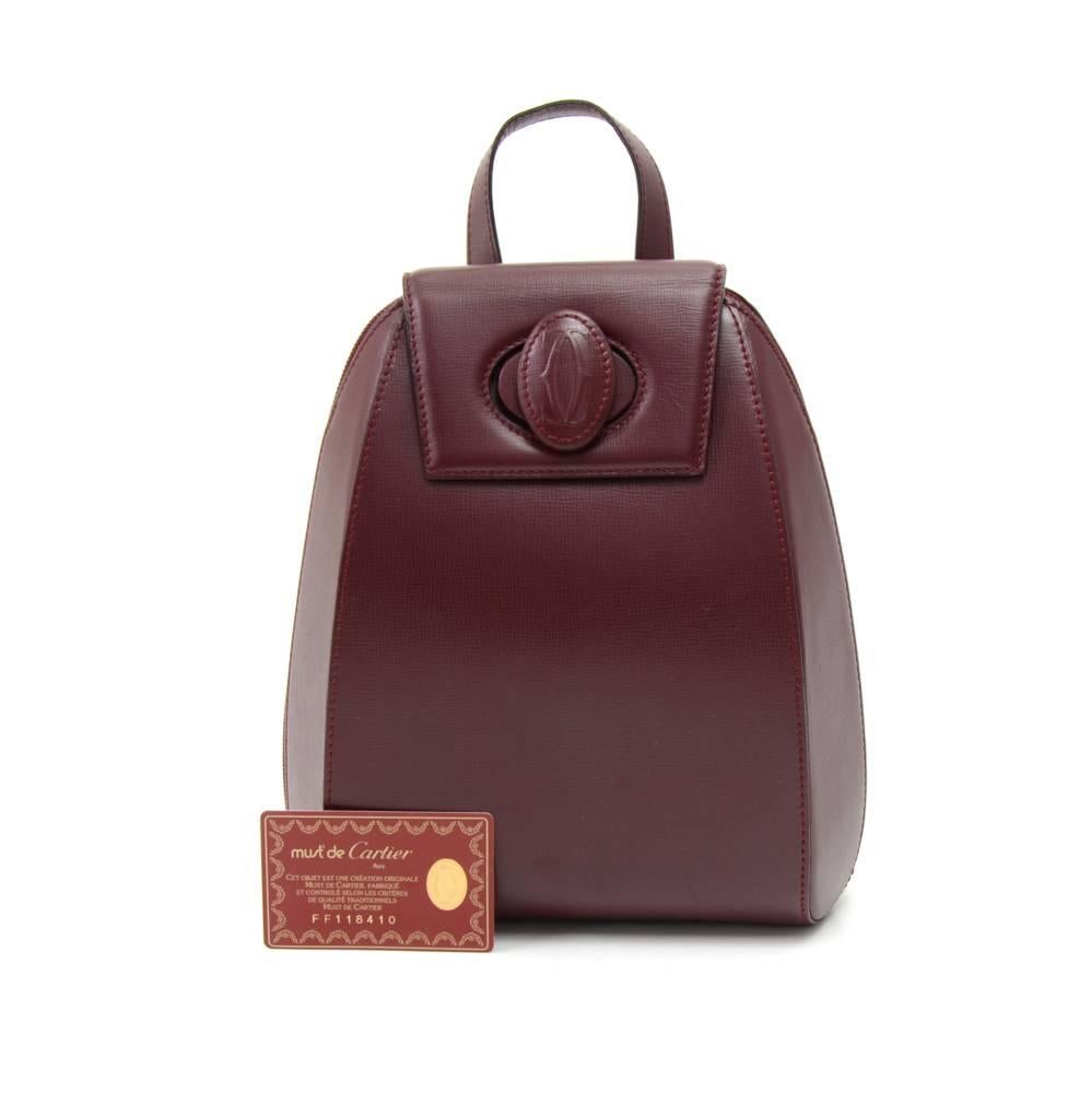 Cartier backpack in lovely burgundy cowhide leather from the Must de Cartier Line. The top is secured with double full-length zipper and small flap with a twist lock. Inside has a fabric monogrammed burgundy lining with 1 zipper pocket. Comes with