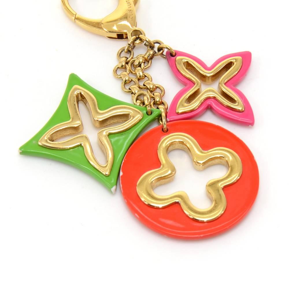 Louis Vuitton gold-tone Monogram Flowers Key holder/key chain or bag charm. It has orange, fuschia, and green plastic charms of the classic Louis Vuitton Monogram flowers.  Great way to accessorize your items! SKU: LO320

Size: 5.9 x 2 x x inches or